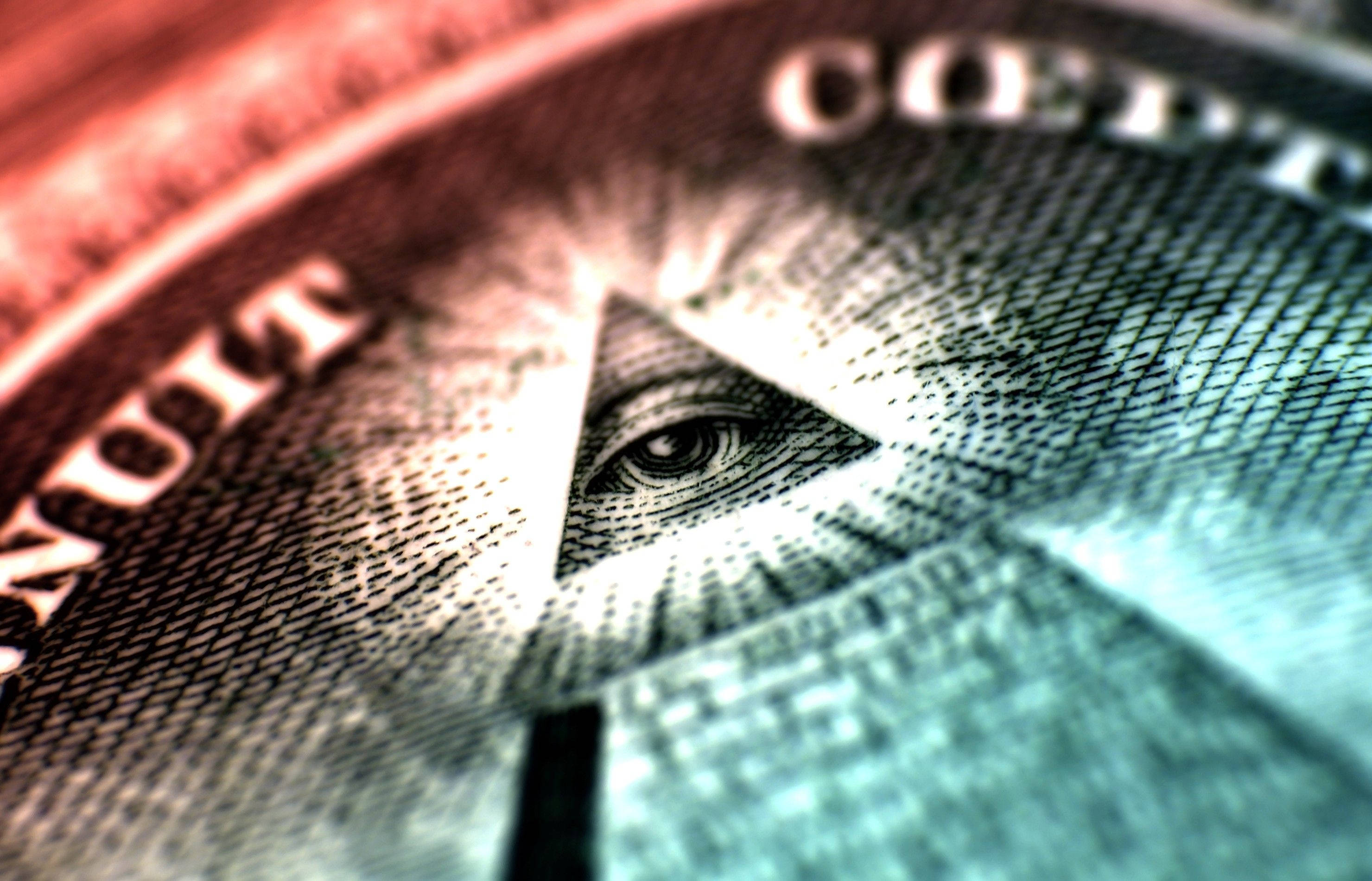 illuminati 桌布 壁紙 — 一美元紙幣上上帝之眼的特寫，焦點銳利在眼睛上，文字模糊，色調為紅色和藍綠色。