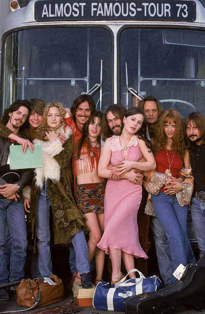電影動圖 桌布 壁紙 — 一群1970年代的嬉皮士在標有「ALMOST FAMOUS-TOUR 73」的旅遊巴士前，帶著復古行李愉快地擺姿勢。