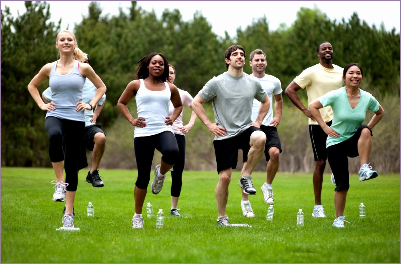 Fitness 桌布 壁紙 — 一群不同背景、面帶笑容的人，充滿活力地在一片綠草如茵、樹木林立的田野上慢跑。