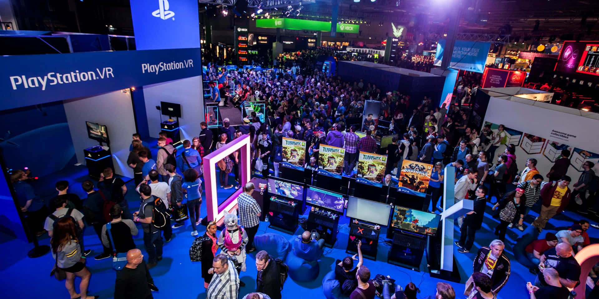 Gaming Conventions 桌布 壁紙 — 一群人在遊戲展覽中探索PlayStation VR展位，周圍是明亮的藍色和紫色燈光。