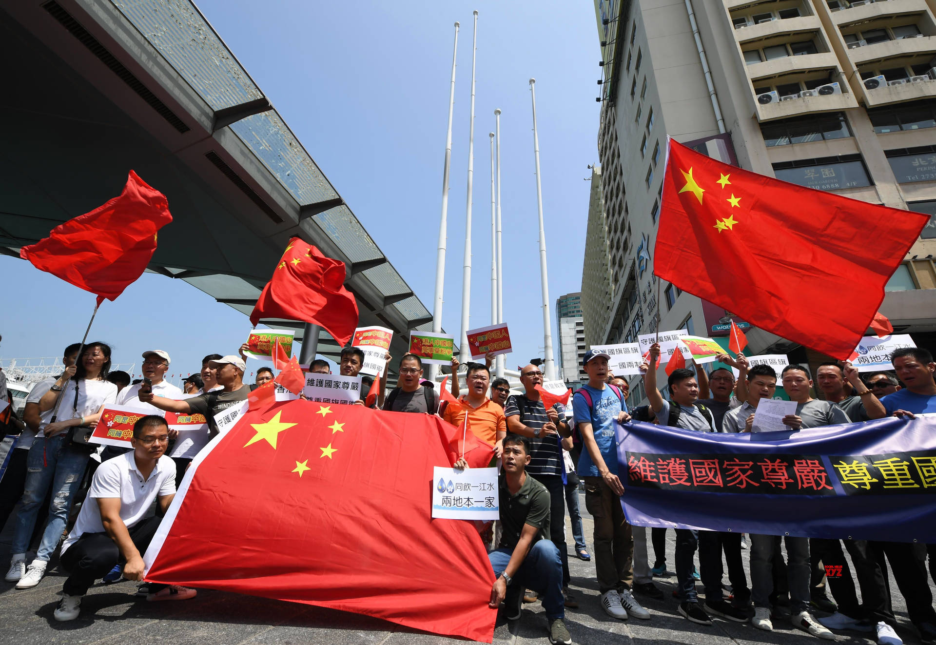 抗議者在城市街道上白天手持中國國旗和標語。