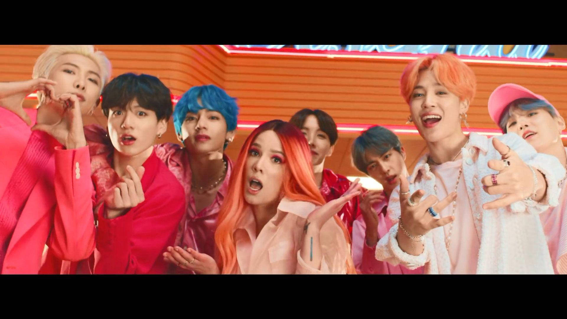 BTS 桌布 桌布 壁紙 — 一群充滿活力的K-pop偶像，擁有色彩繽紛的頭髮和大膽的服裝，在發光的橙色霓虹燈背景下充滿活力地擺姿勢。