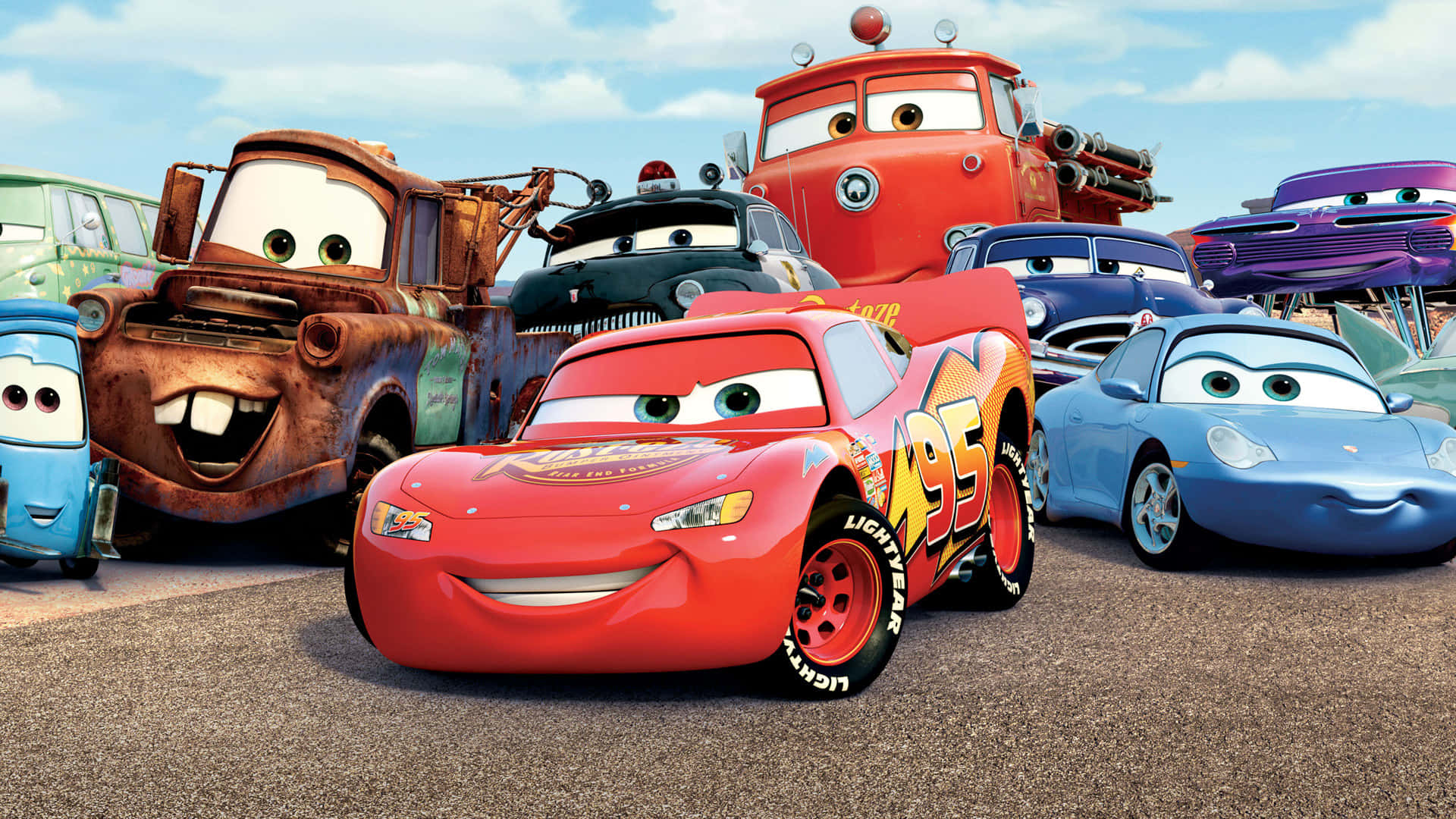 Lightning Mcqueen 桌布 壁紙 — 一群充滿活力的動畫擬人化賽車，表情豐富，聚集在陽光明媚的瀝青賽道上。