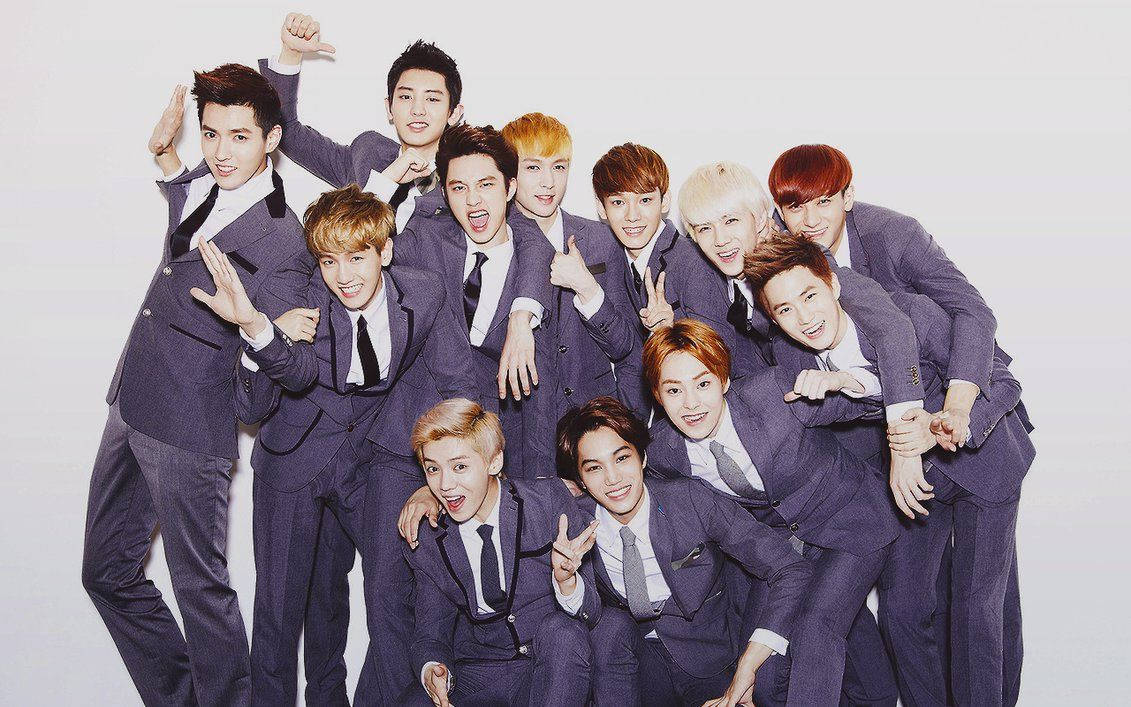 K-pop 桌布 壁紙 — 一群充滿活力的年輕男子穿著相配的紫色西裝，在純白色背景前擺出俏皮的姿勢。