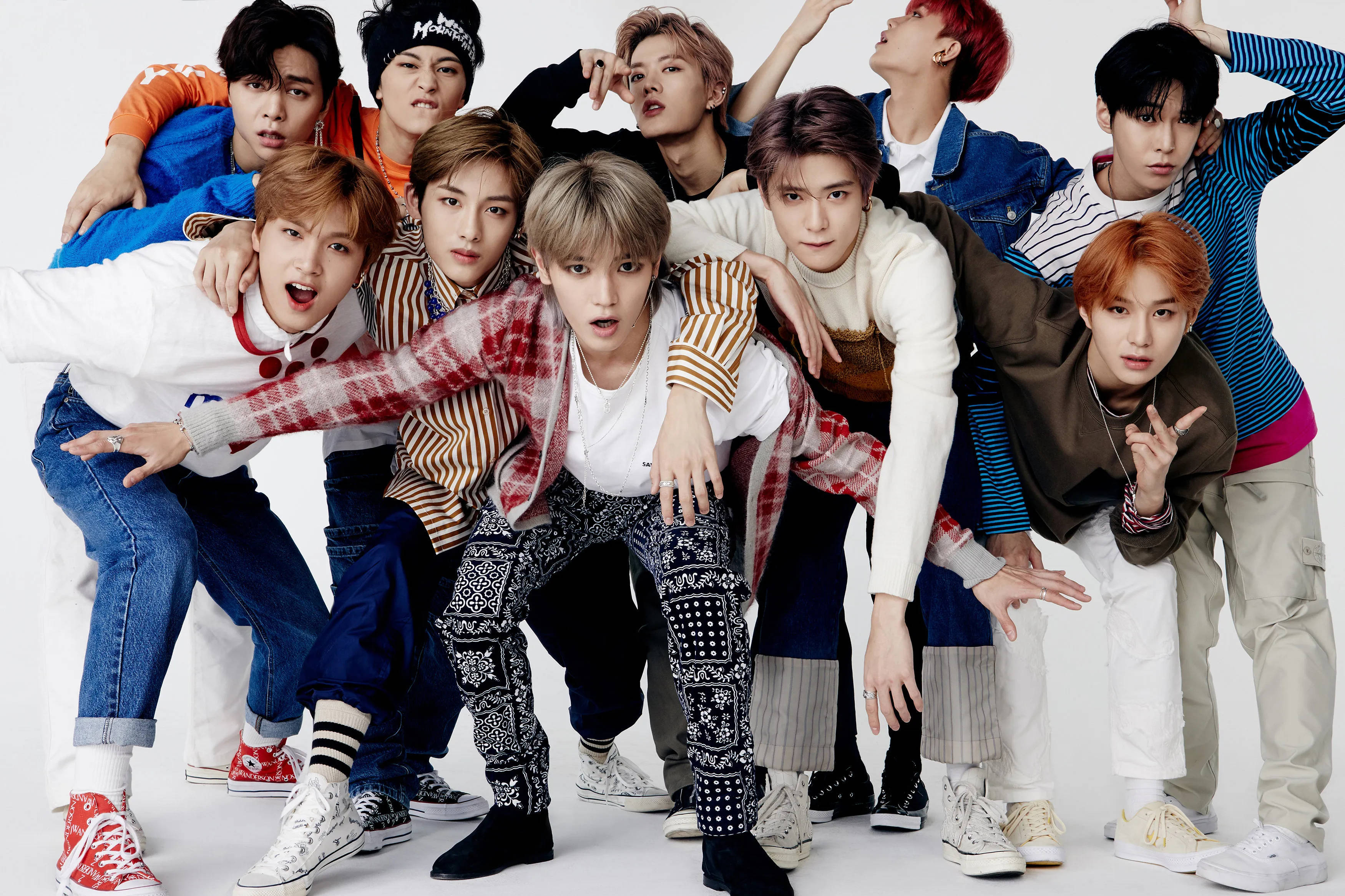 Nct 桌布 壁紙 — 一群充滿活力的年輕男子穿著色彩繽紛的街頭服飾，在純白色背景前擺出俏皮的姿勢。