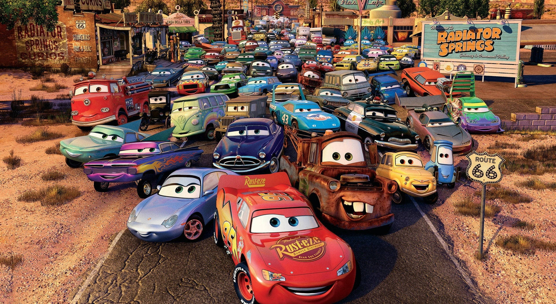 Pixar 桌布 壁紙 — 一群充滿活力的擬人化汽車在溫暖的金色光芒下聚集在塵土飛揚的沙漠小鎮 Radiator Springs。