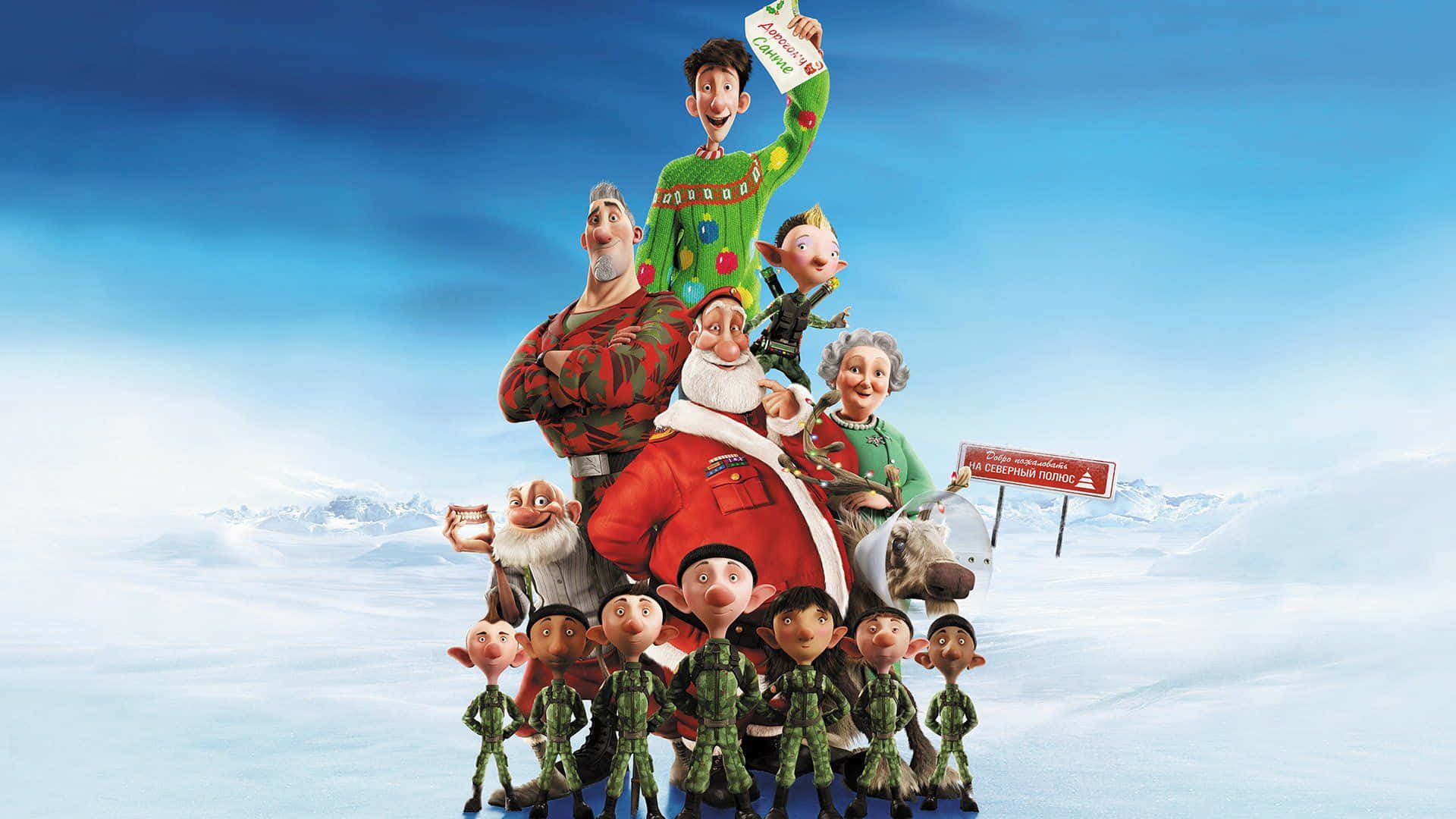 Christmas Movie 桌布 壁紙 — 一群動畫角色，包括聖誕老人和精靈，站在白雪覆蓋的山頂上，天空湛藍明亮。