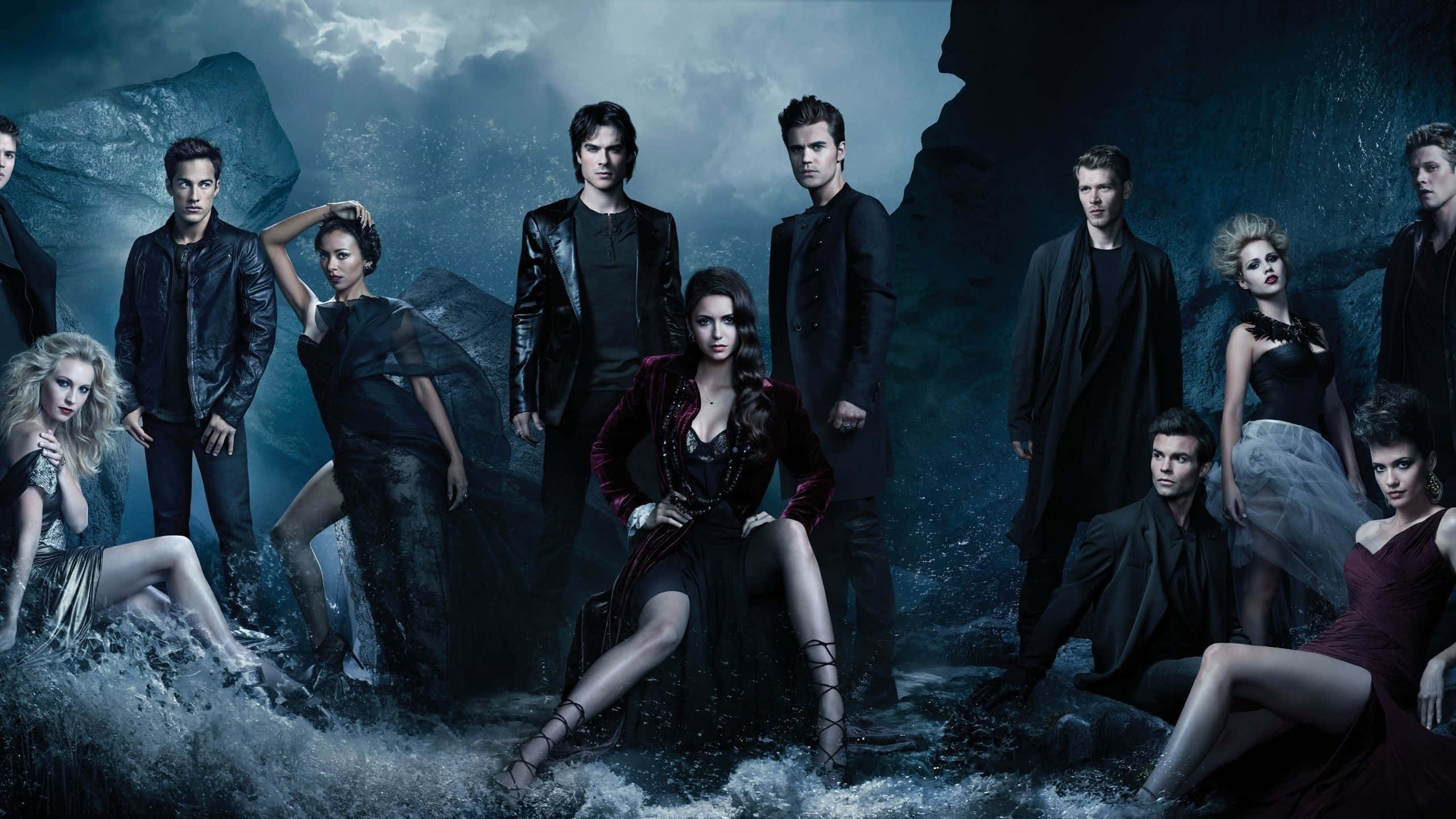 Vampire Diaries Desktop 桌布 壁紙 — 一群吸血鬼和人類在黑暗天空下的暴風雨岩石海岸場景中戲劇性地擺姿勢。