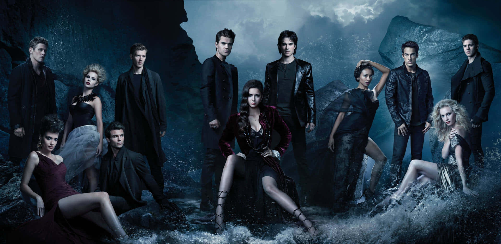 The Vampire Diaries iPhone 桌布 壁紙 — 一群吸血鬼和狼人在風暴洞穴中戲劇性地擺姿勢，伴隨著洶湧的水流和深藍色燈光。