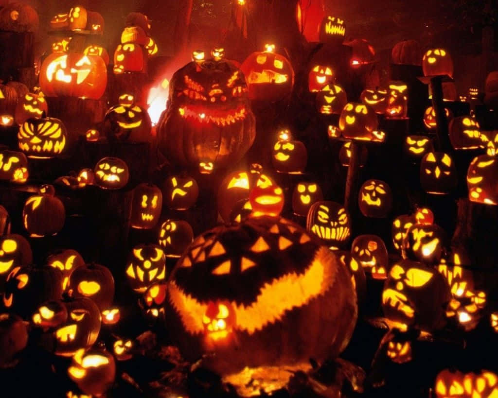 pumpkins 桌布 壁紙 — 一群密集的發光南瓜燈，帶有兇惡的雕刻面孔，照亮了黑暗詭異的萬聖節場景。