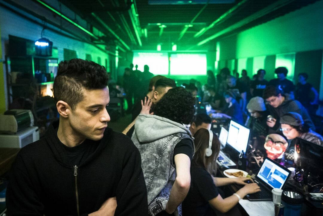 Rami Malek 桌布 壁紙 — 一群年輕人在昏暗的房間中，被充滿活力的綠色霓虹燈光沐浴，激烈地玩遊戲。