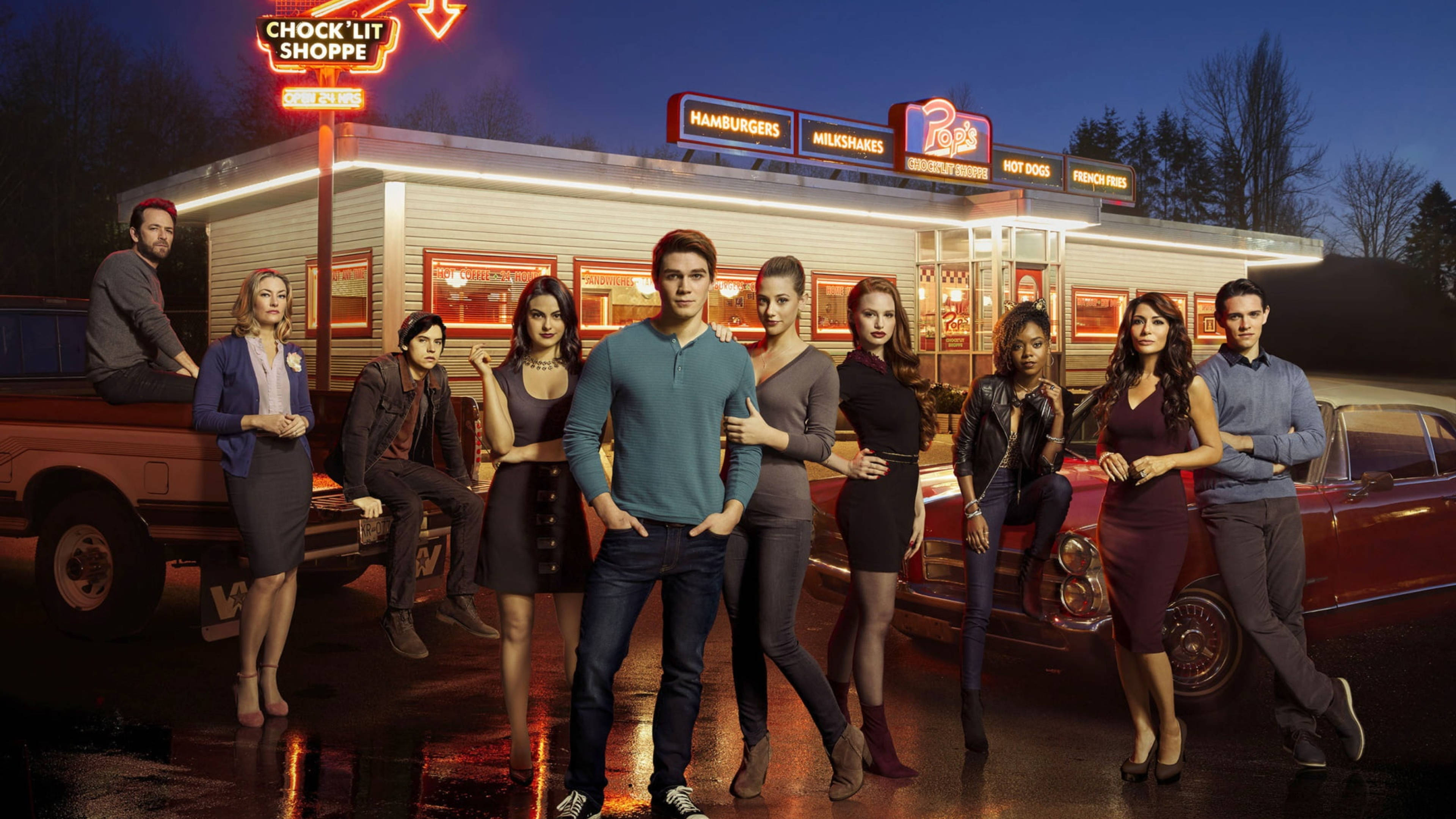 Riverdale 桌布 壁紙 — 一群年輕成年人在夜間自信地站在復古餐廳前，霓虹燈招牌映照在濕漉漉的路面上。