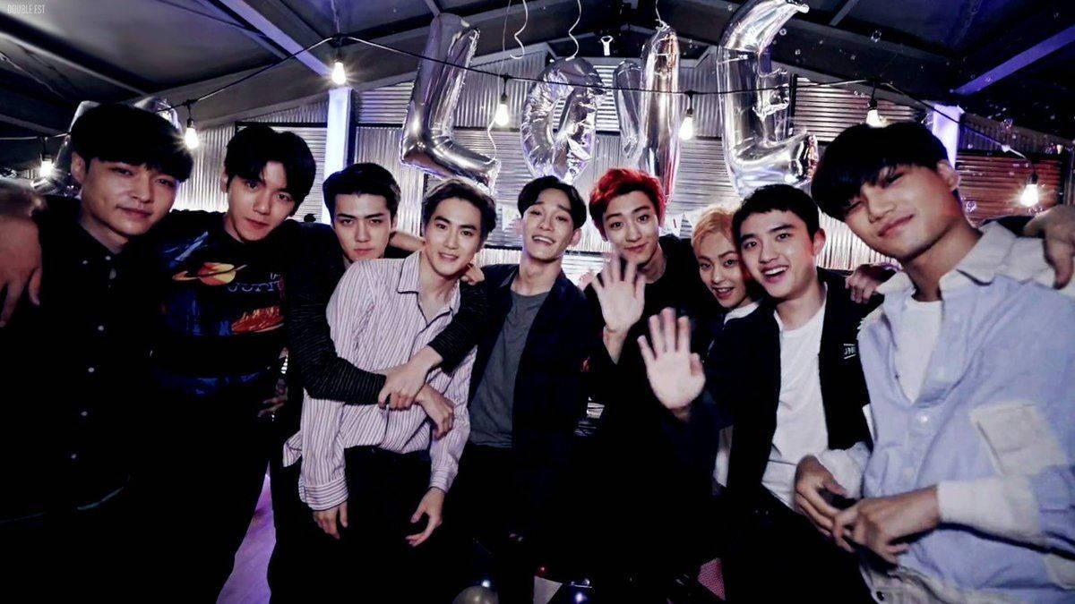 K-pop 桌布 壁紙 — 一群年輕男子在昏暗的室內空間中，在串燈下與大型銀色 LOVE 氣球一起擺姿勢。