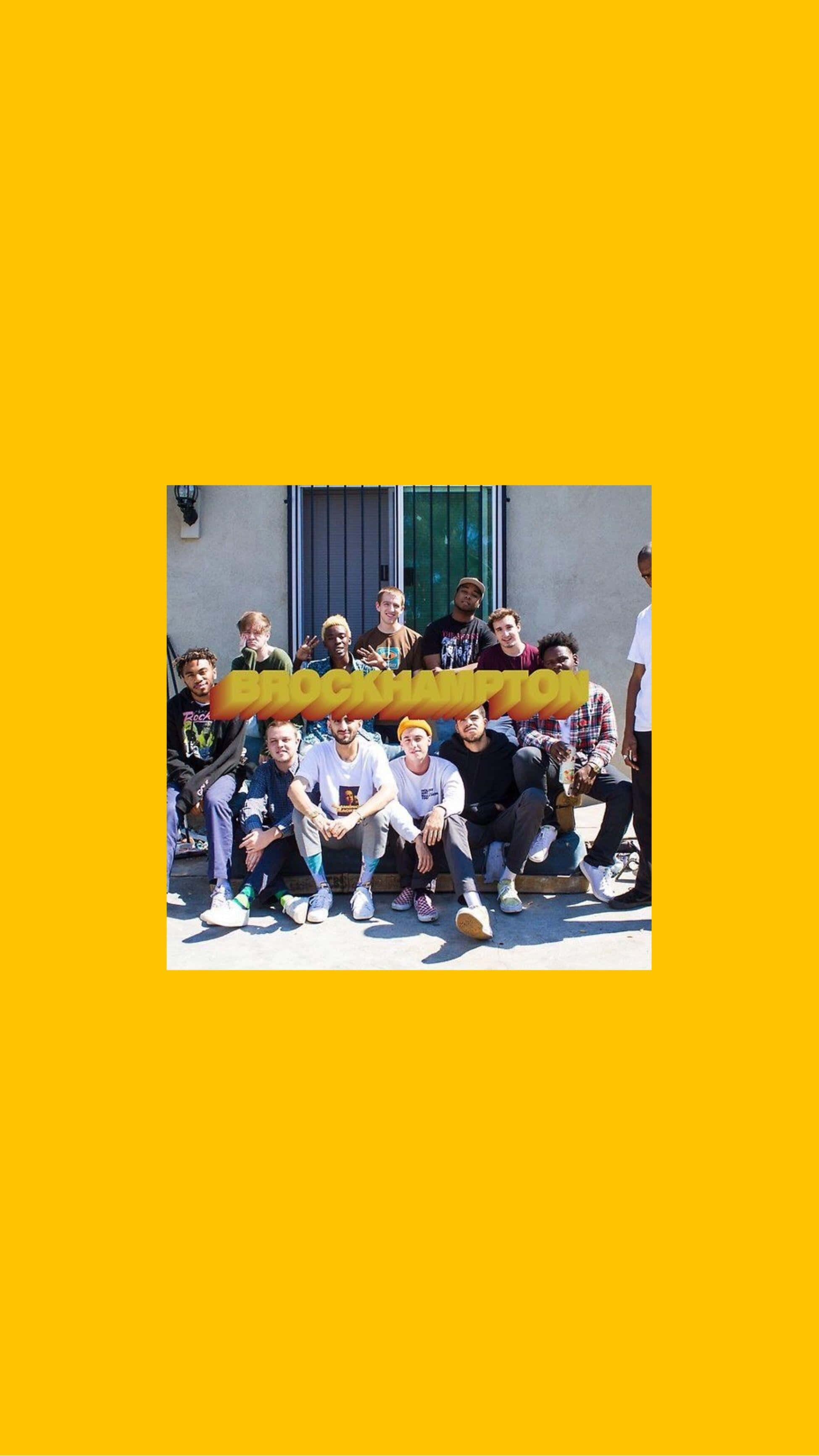 Brockhampton 桌布 壁紙 — 一群年輕男性在明亮的陽光下，靠著素牆，隨意地坐在長椅上擺姿勢，並帶有粗體黃色文字疊加。