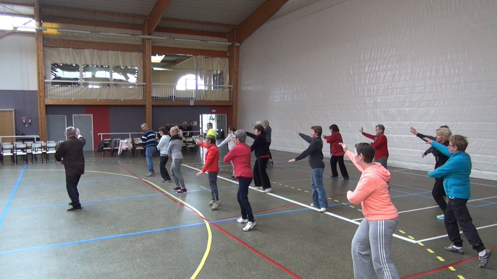 martial arts 桌布 壁紙 — 一群成年人在體育館穿著色彩繽紛的運動服進行同步舞蹈動作。