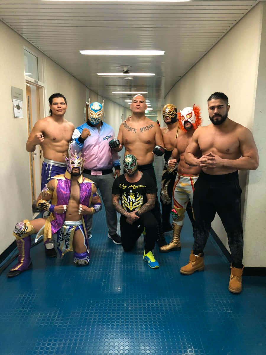 UFC 桌布 壁紙 — 一群戴著色彩繽紛面具和服裝的摔角手，在鋪有藍色磁磚的狹窄走廊上自信地擺姿勢。