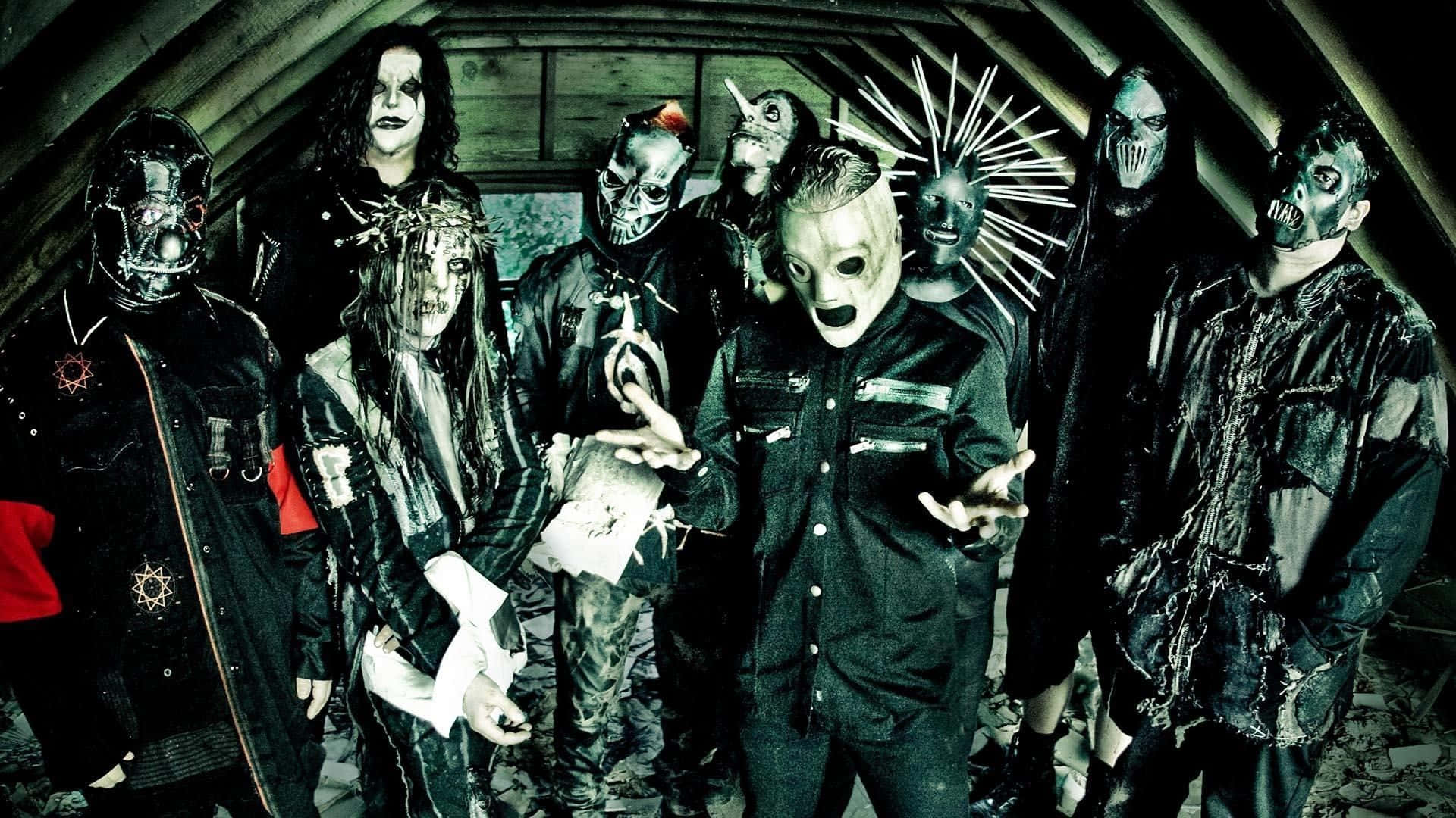 Slipknot 桌布 壁紙 — 一群戴著面具、身穿暗黑哥德式服裝的音樂家在光線昏暗的木質閣樓中擺出威脅姿態。