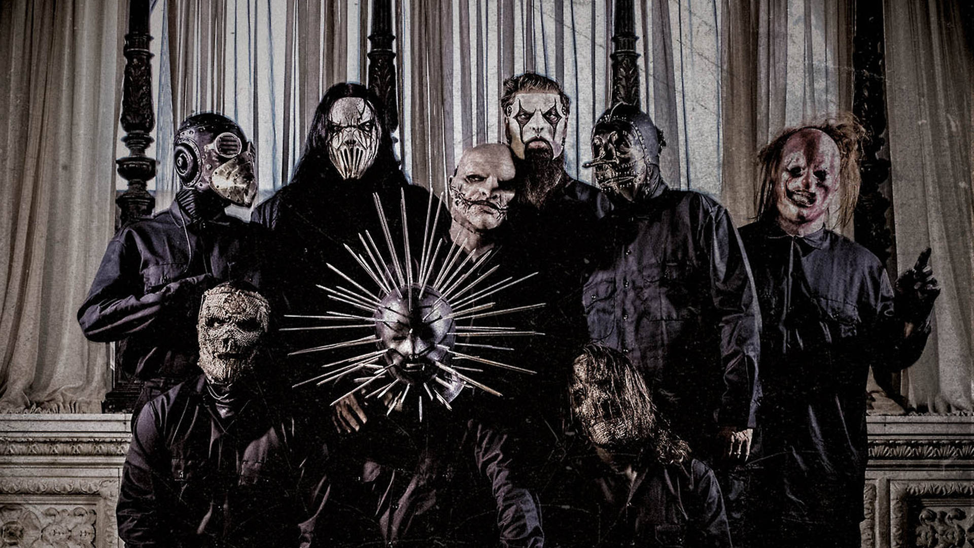 craig jones 桌布 壁紙 — 一群戴著面具、身穿深色衣服的人物在一個哥德式房間裡擺出威脅性的姿勢，房間裡有華麗的窗簾和一個帶尖刺的太陽爆發面具作為中心裝飾。