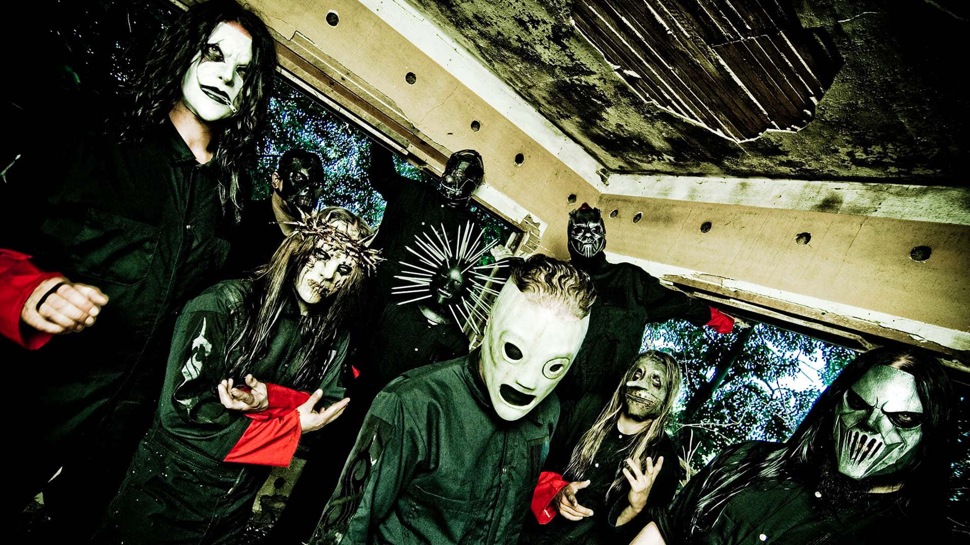 Slipknot 桌布 壁紙 — 一群戴著面具、身穿深色衣服的音樂家在一個破舊、佈滿塗鴉的城市建築內戲劇性地擺姿勢。