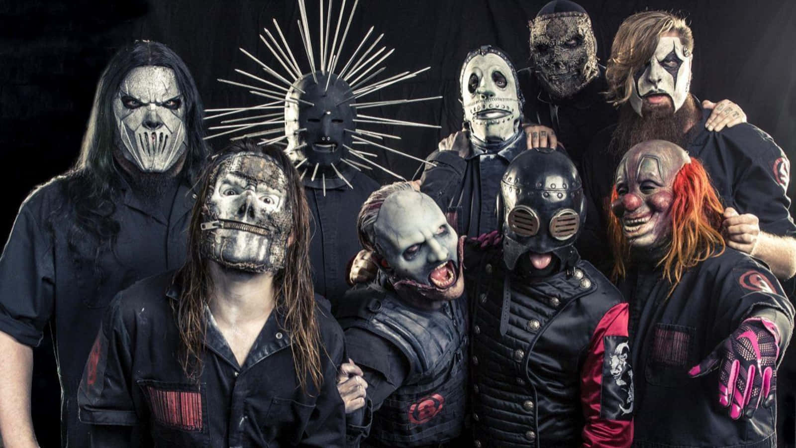 Slipknot 桌布 壁紙 — 一群戴著面具的音樂家，化著怪誕的妝容，穿著深色衣服，在黑色背景下強烈地擺姿勢。