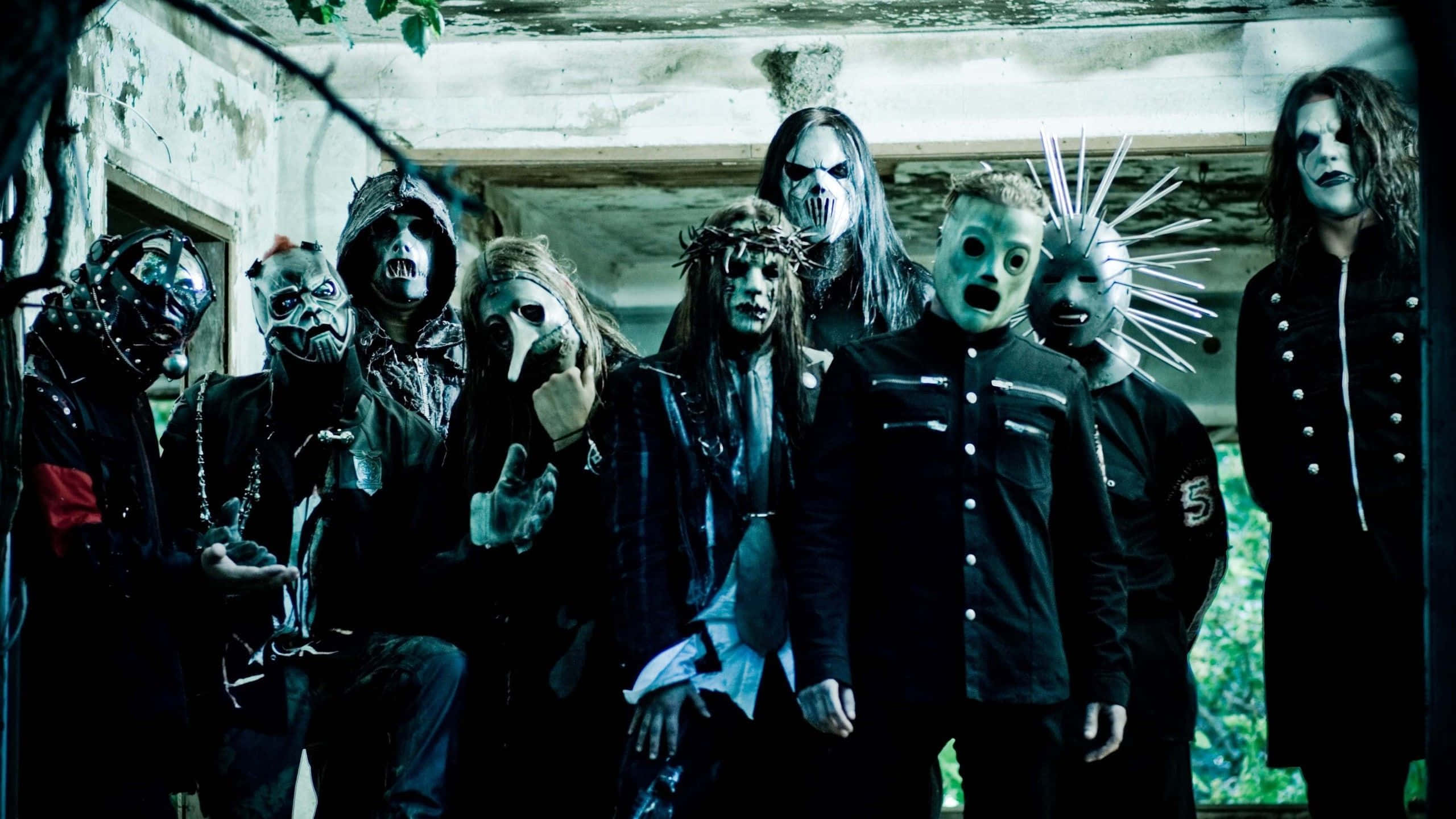 Slipknot 桌布 壁紙 — 一群戴著面具的音樂家身穿暗黑哥德式服裝，在一個破舊的建築物中，在詭異的綠色燈光下擺出威脅性的姿勢。