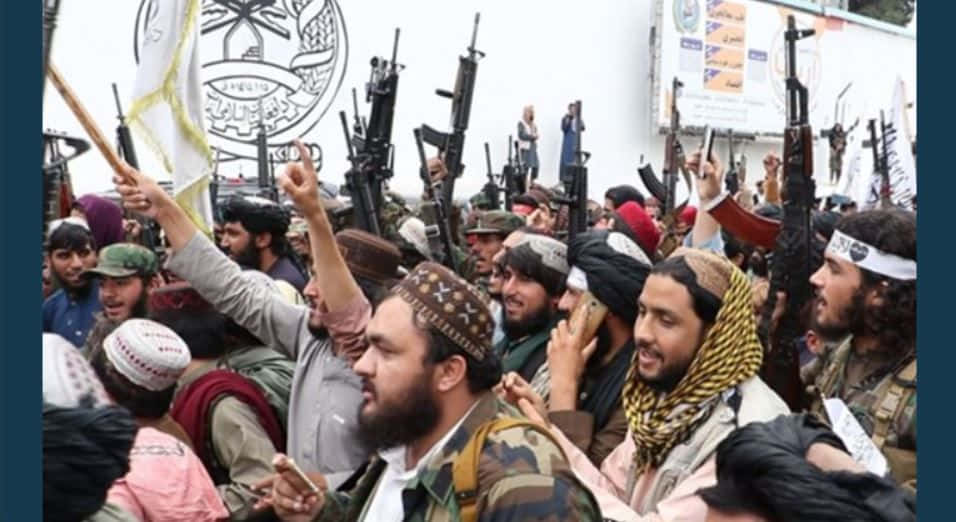 Taliban 桌布 壁紙 — 一群戴著頭巾和頭巾的武裝男子在緊張的戶外聚會中舉起步槍和旗幟。