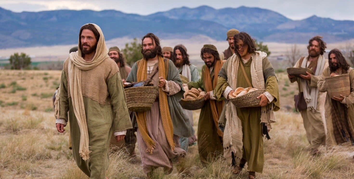 Jesus Disciples 桌布 壁紙 — 一群穿著古代長袍的男人走過乾燥的草地平原，提著裝有麵包的籃子，背景有山脈。