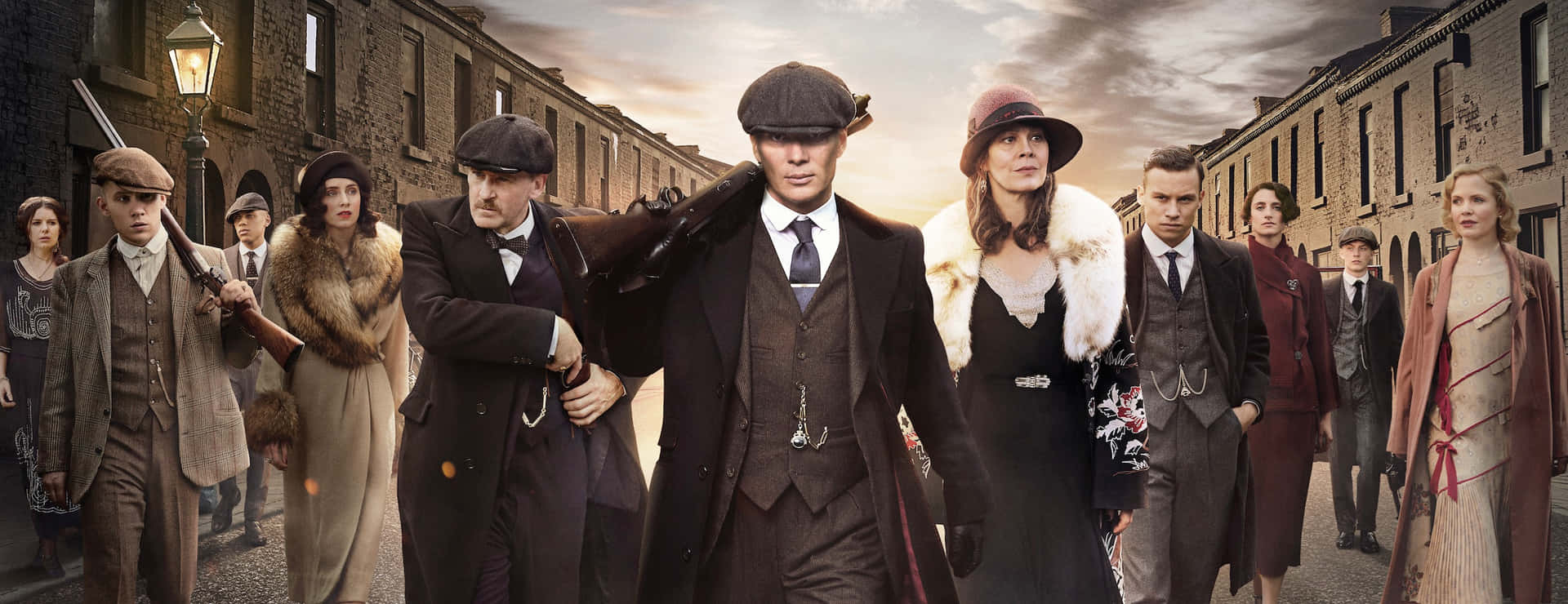 一群1920年代的幫派分子穿著大衣和帽子走在磚街上。 — Peaky Blinders 壁紙