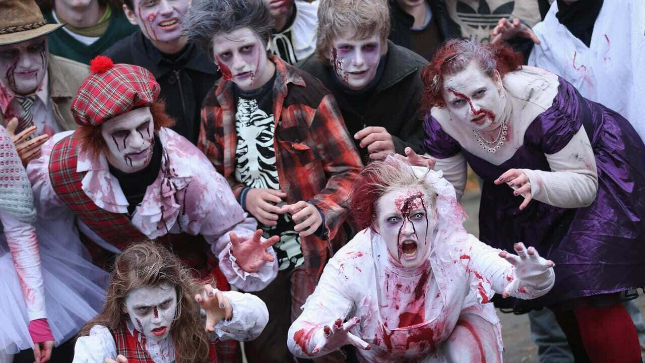 Scary Zombie 桌布 壁紙 — 一群穿著恐怖殭屍服裝、帶有假血和蒼白化妝的人，擺出威脅姿勢拍照。