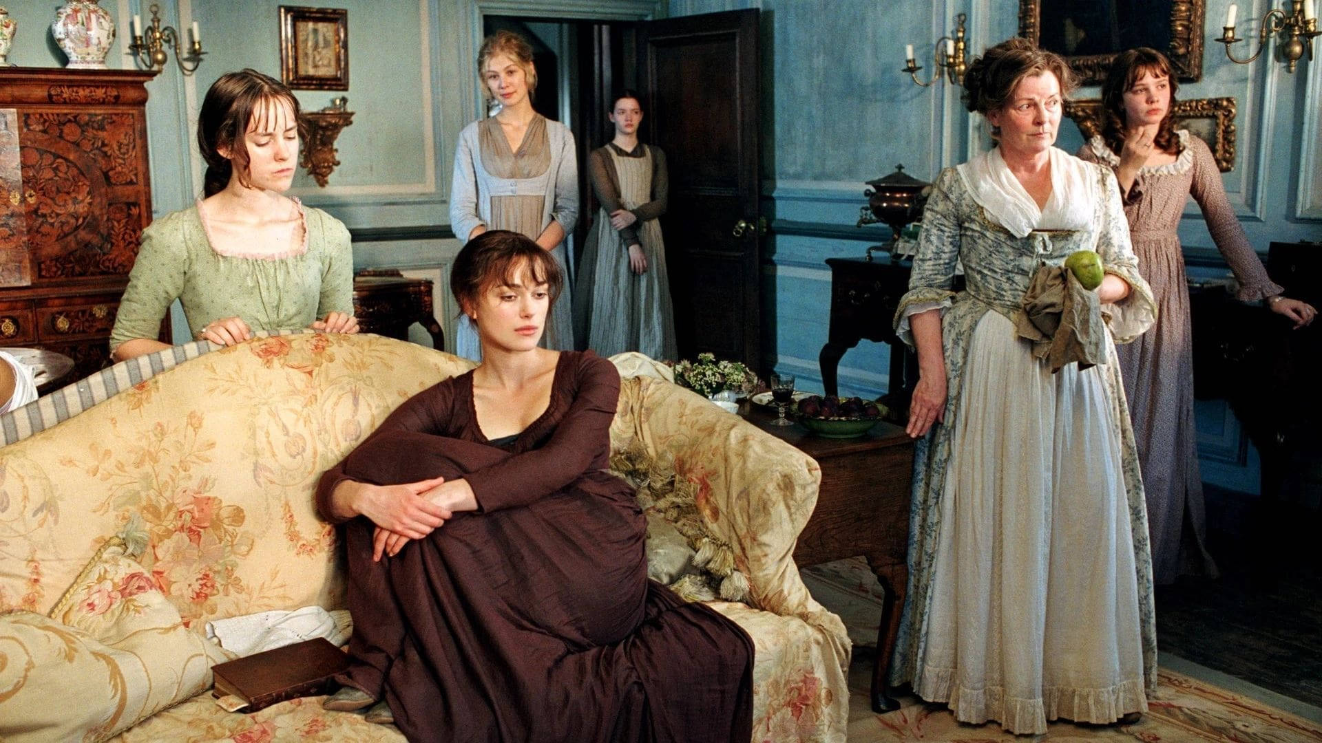 Pride And Prejudice 桌布 壁紙 — 一群穿著時代服裝的女性站在和坐在一個裝飾華麗的藍色牆壁客廳裡，裡面擺滿了古董家具。