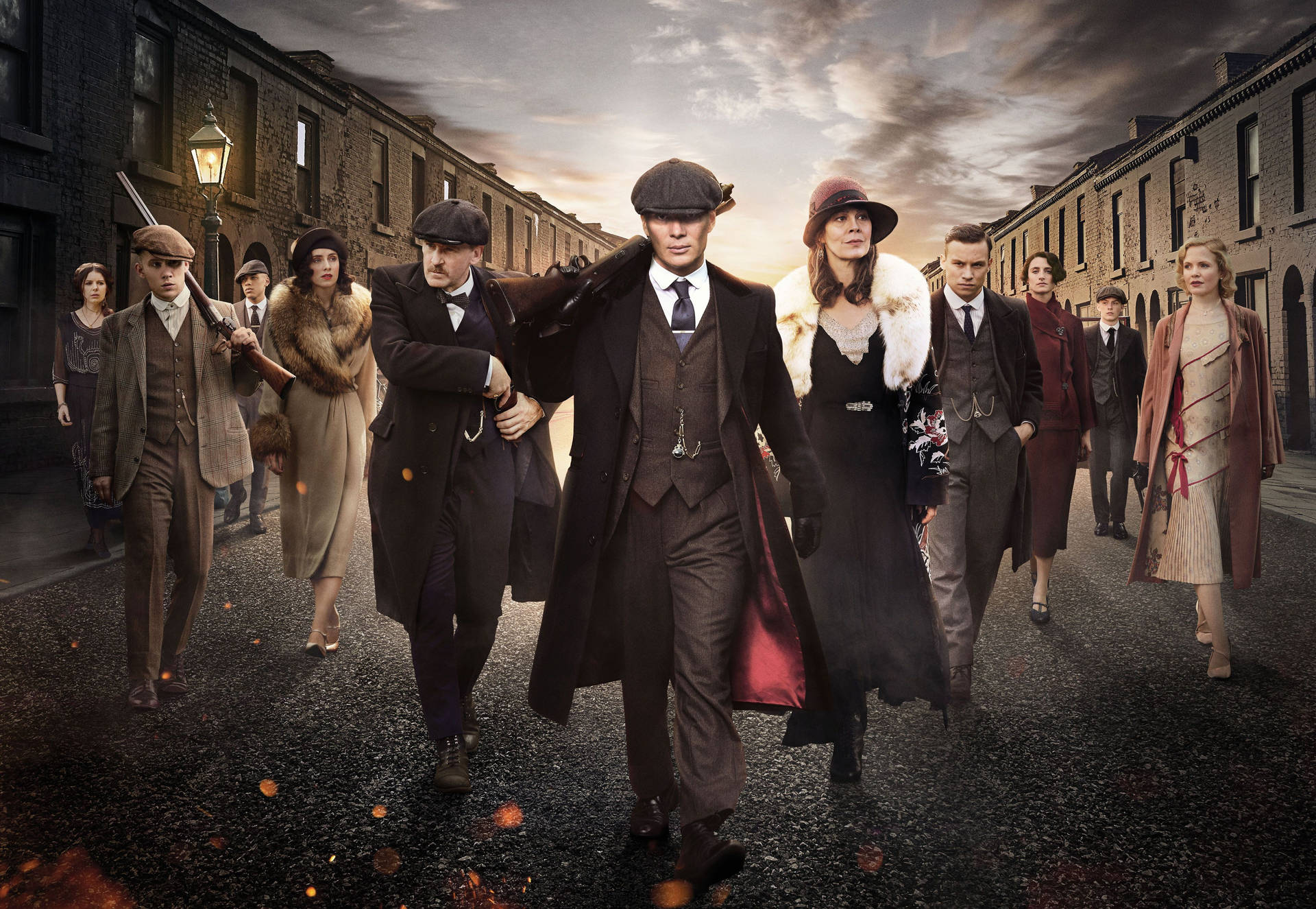 一群1920年代的幫派分子在日落時分沿著磚街行走。 — Peaky Blinders 壁紙