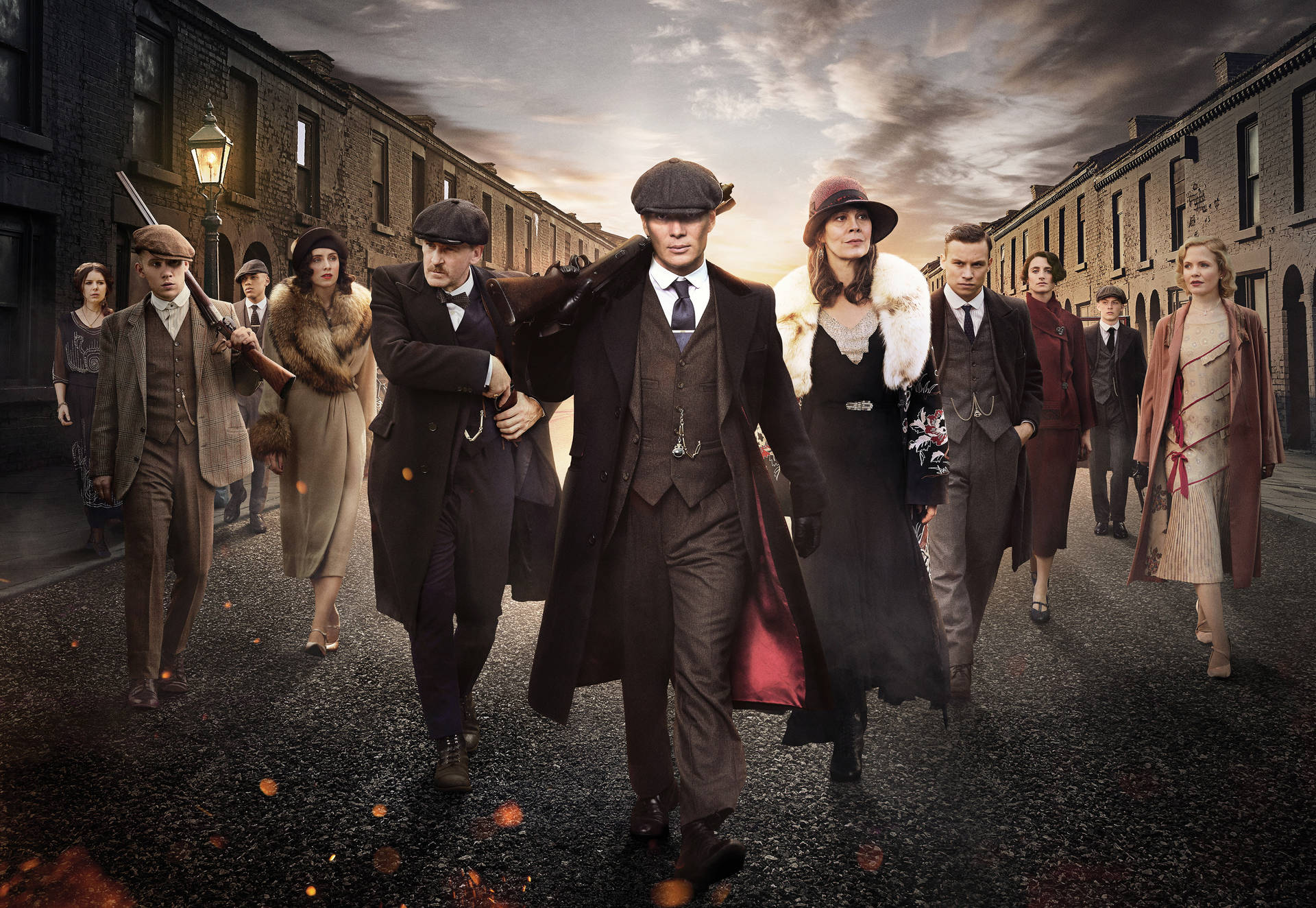 一群1920年代的幫派分子在黃昏時分沿著一條昏暗的街道行走。 — Peaky Blinders 壁紙