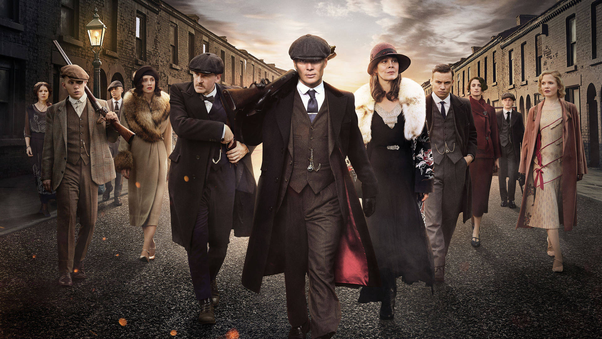 一群穿著1920年代服裝的男女在黃昏時分走在磚砌街道上。 — Peaky Blinders 壁紙