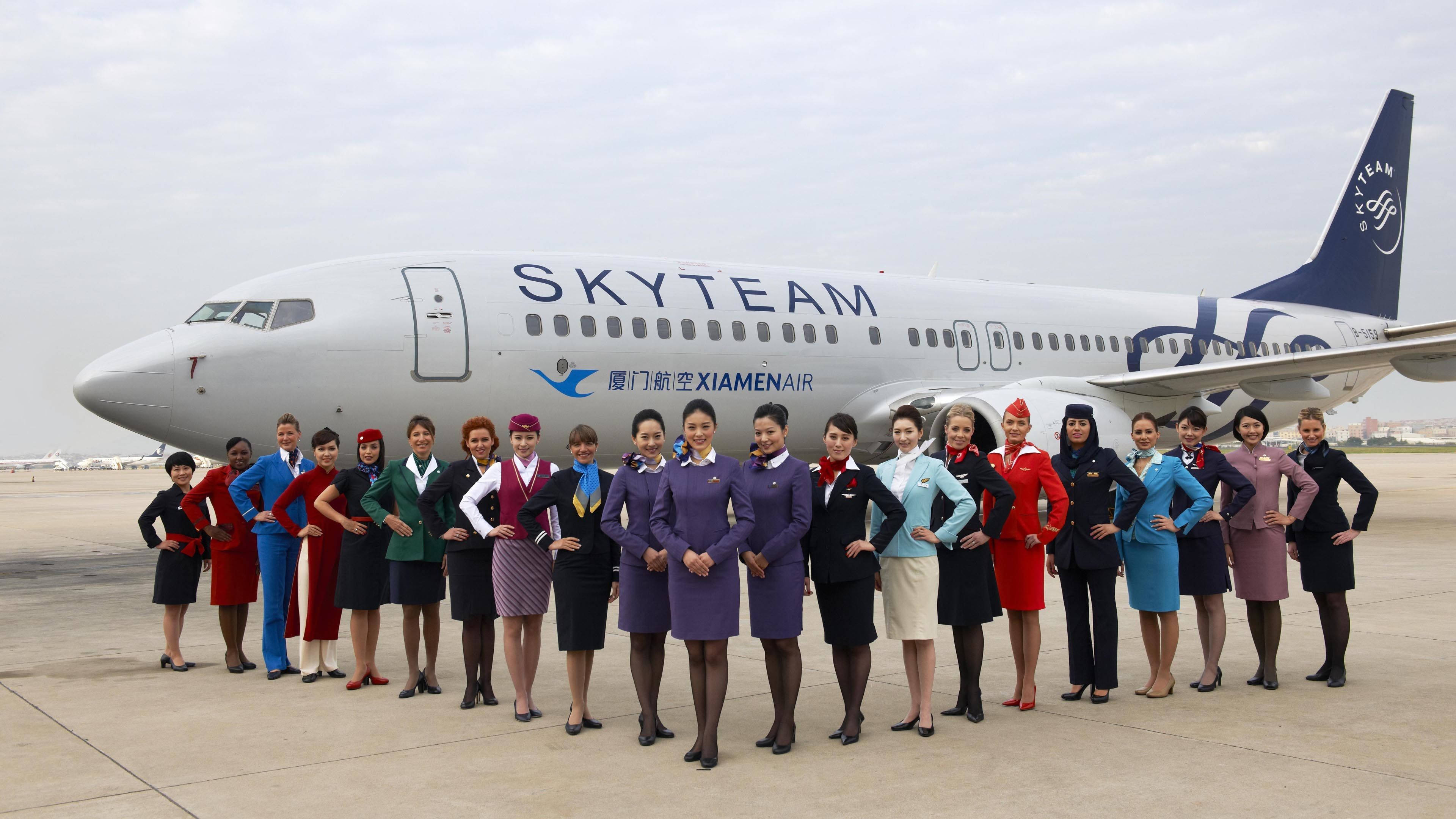 Airport 桌布 壁紙 — 一群穿著色彩繽紛制服的空中服務員在機場停機坪上，自信地站在天合聯盟廈門航空飛機前擺姿勢。