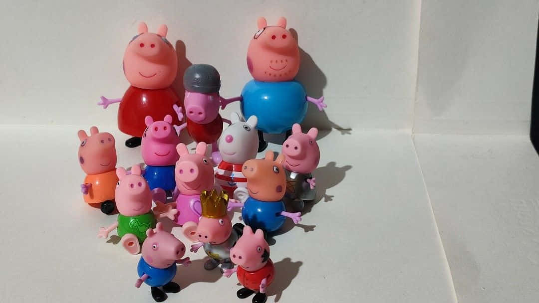 Peppa Pig Family 桌布 壁紙 — 一群穿著色彩繽紛服裝的Peppa Pig玩具公仔，開心地一起擺放在純白色表面上。