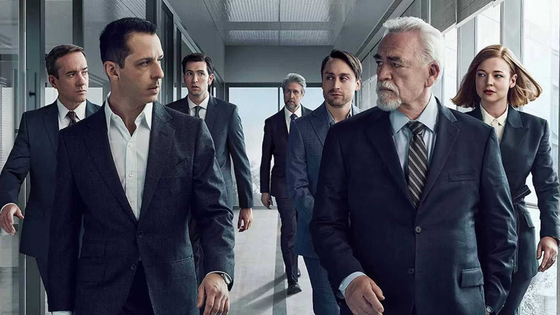 Succession 桌布 壁紙 — 一群穿著西裝的嚴肅專業人士，帶著專注的表情走過現代玻璃牆的辦公室走廊。