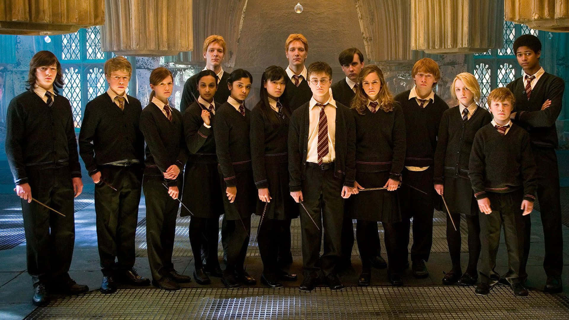 Dumbledore's Army 桌布 壁紙 — 一群穿著黑色校服的年輕巫師站在宏偉的石廳中，手持魔杖。