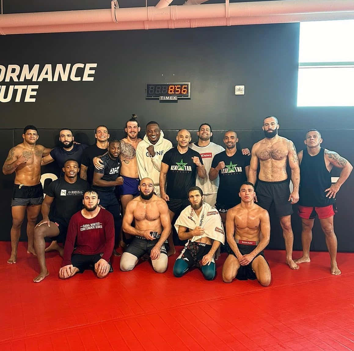 UFC 桌布 壁紙 — 一群肌肉發達的男性戰士在表演學院的健身房的紅色墊子上自信地擺姿勢，牆上有數字計時器。