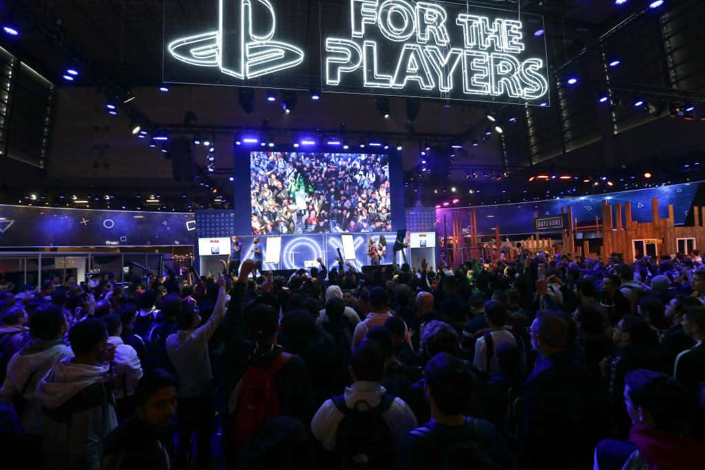 Gaming Tournaments 桌布 壁紙 — 一群興奮的遊戲玩家在PlayStation活動中，在發光的「FOR THE PLAYERS」標誌和大螢幕下。