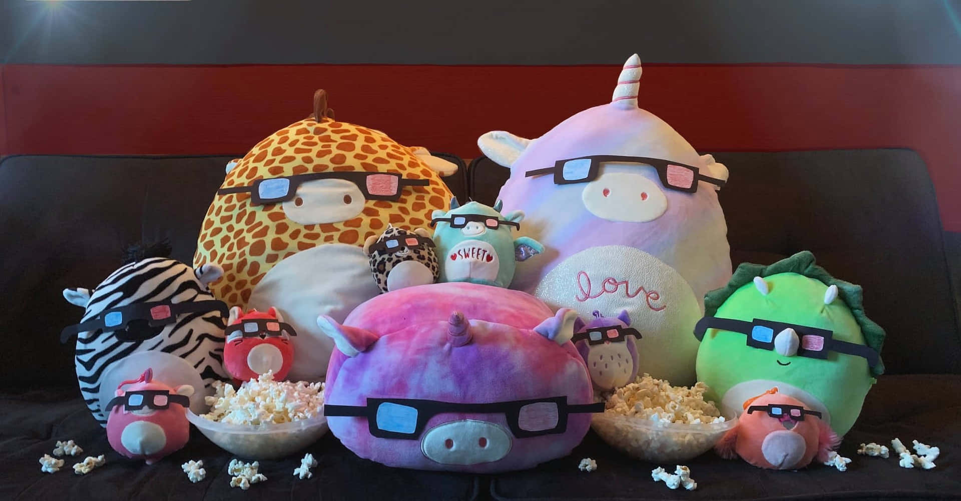 絨毛動物戴著3D眼鏡和爆米花碗在沙發上。 — Squishmallows 壁紙