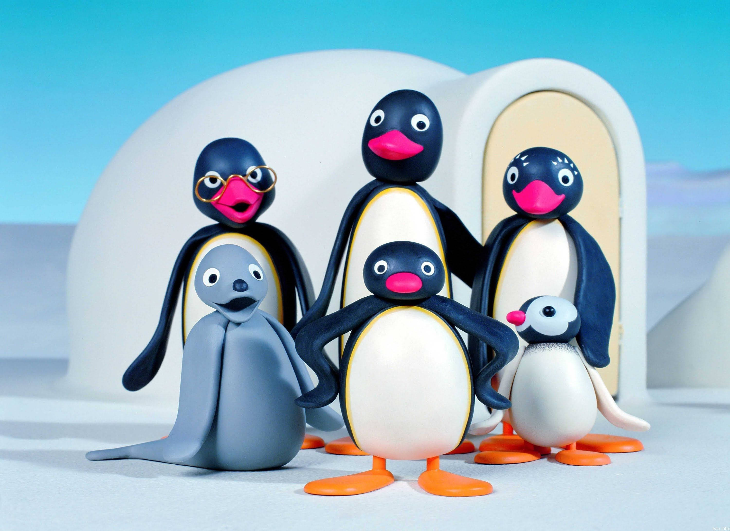 Pingu 桌布 壁紙 — 一群色彩繽紛的黏土企鵝家庭和一隻海豹一起站在冰屋前，背景是明亮的藍天。