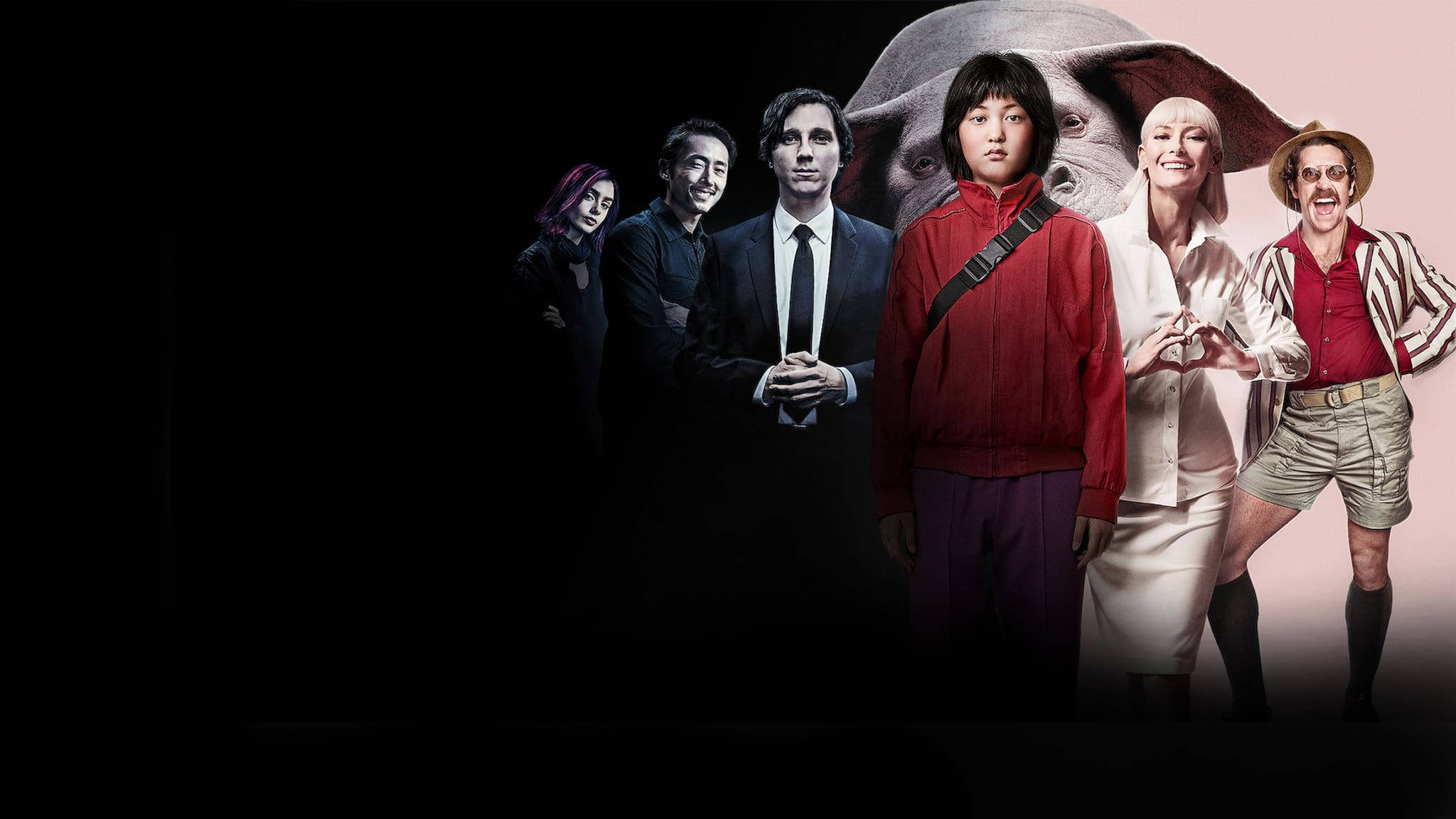 okja 桌布 壁紙 — 一群表情和服裝各異的角色站在黑暗背景前，身後有一個巨大的大象頭若隱若現。