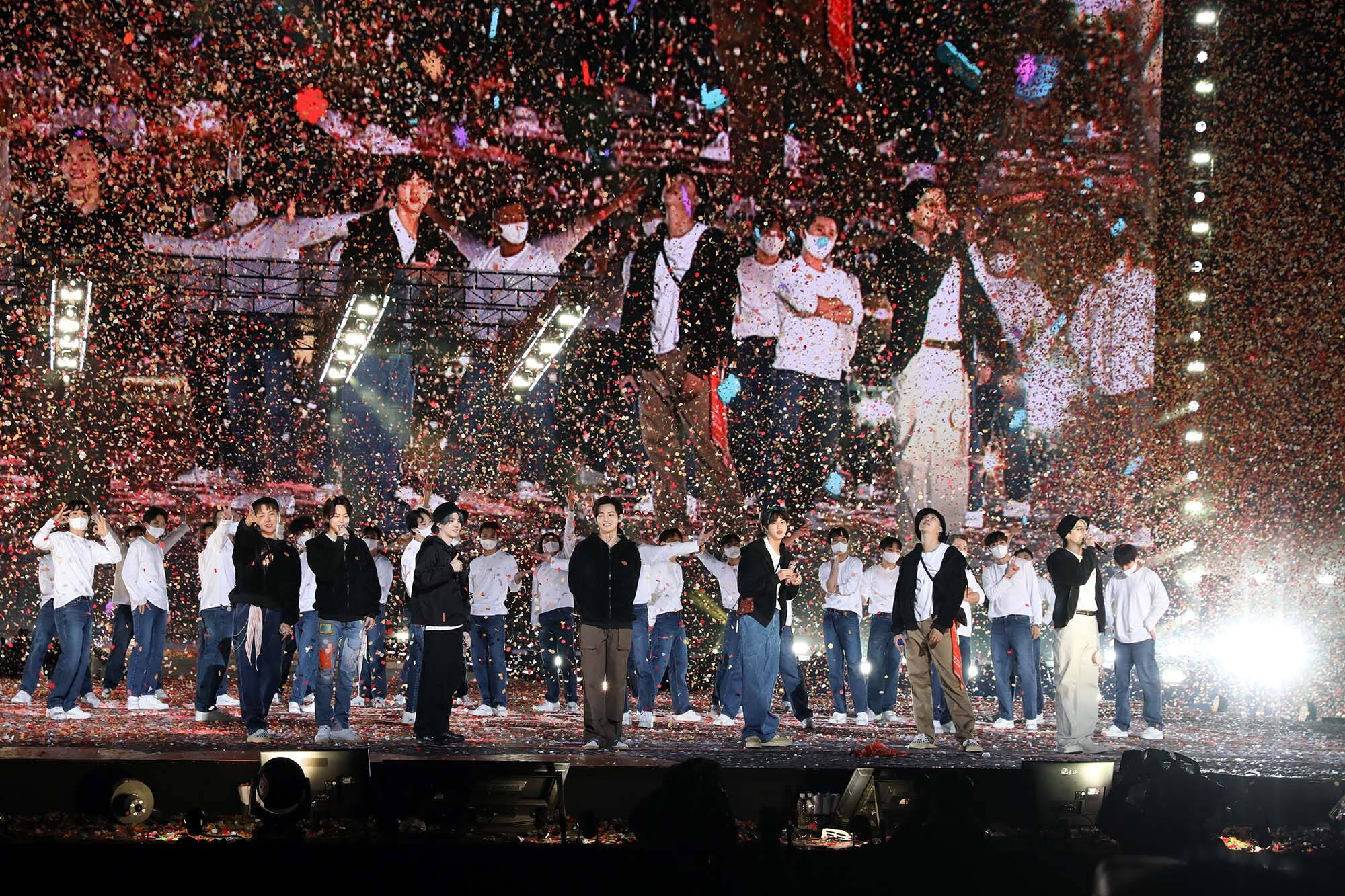 BTS 桌布 壁紙 — 一群表演者在舞台上，在明亮的舞台燈光下，沐浴在五彩紙屑中慶祝。