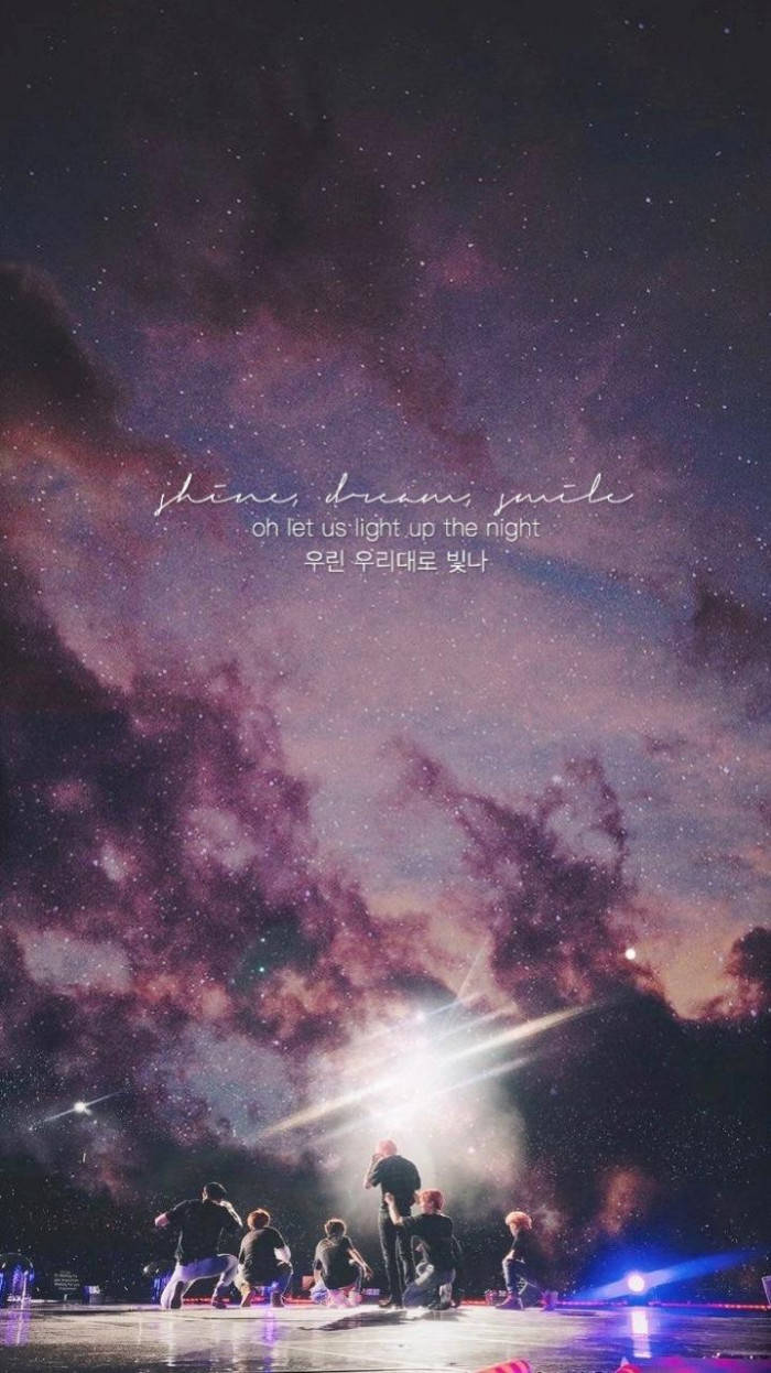Bts Aesthetic 桌布 壁紙 — 一群表演者在舞台上，背景是充滿活力的紫色和粉紅色星空，帶有發光文字疊加。