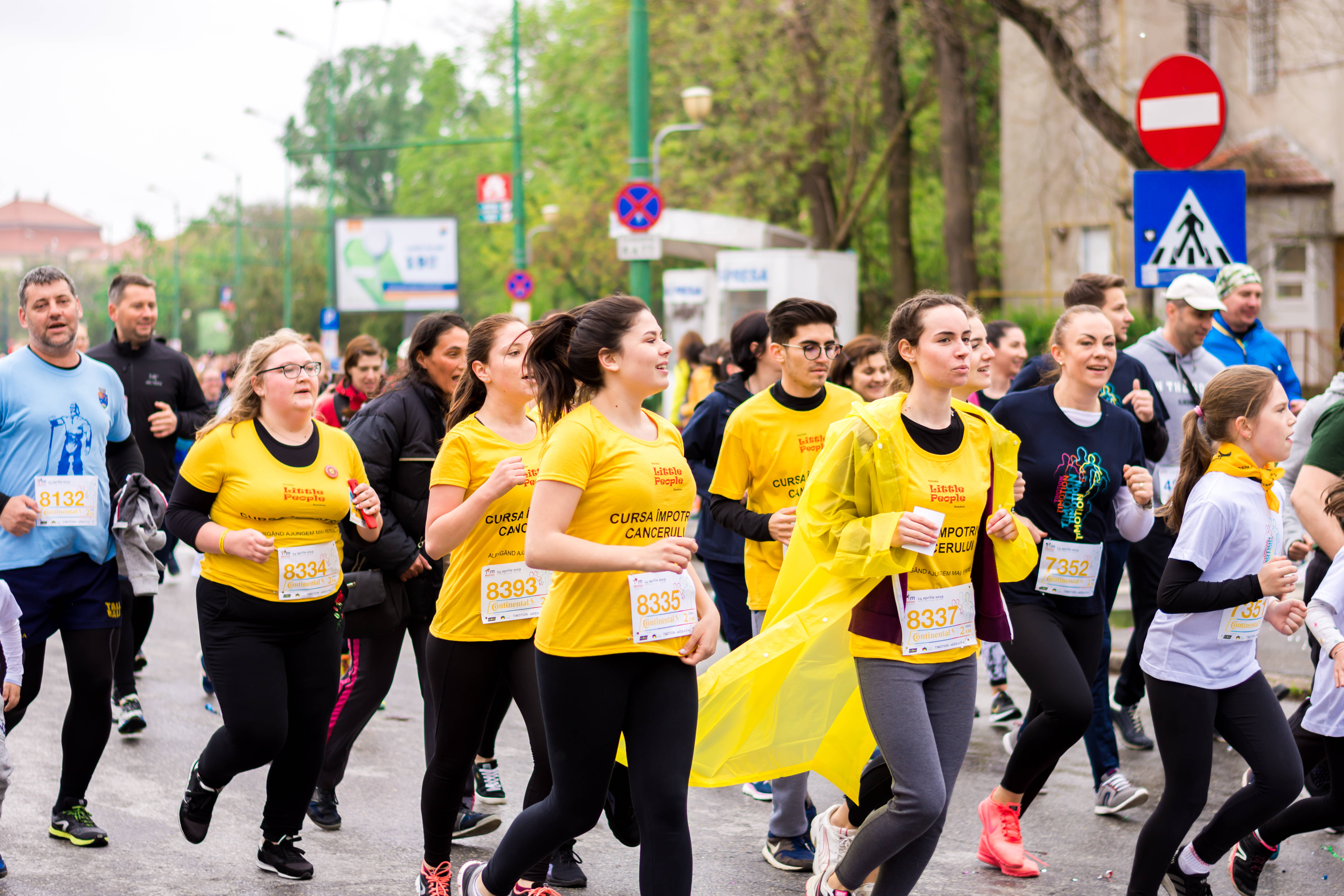 Marathon 桌布 壁紙 — 一群身穿亮黃色襯衫的活潑跑者，在慈善賽跑中沿著綠樹成蔭的城市街道大步前行。