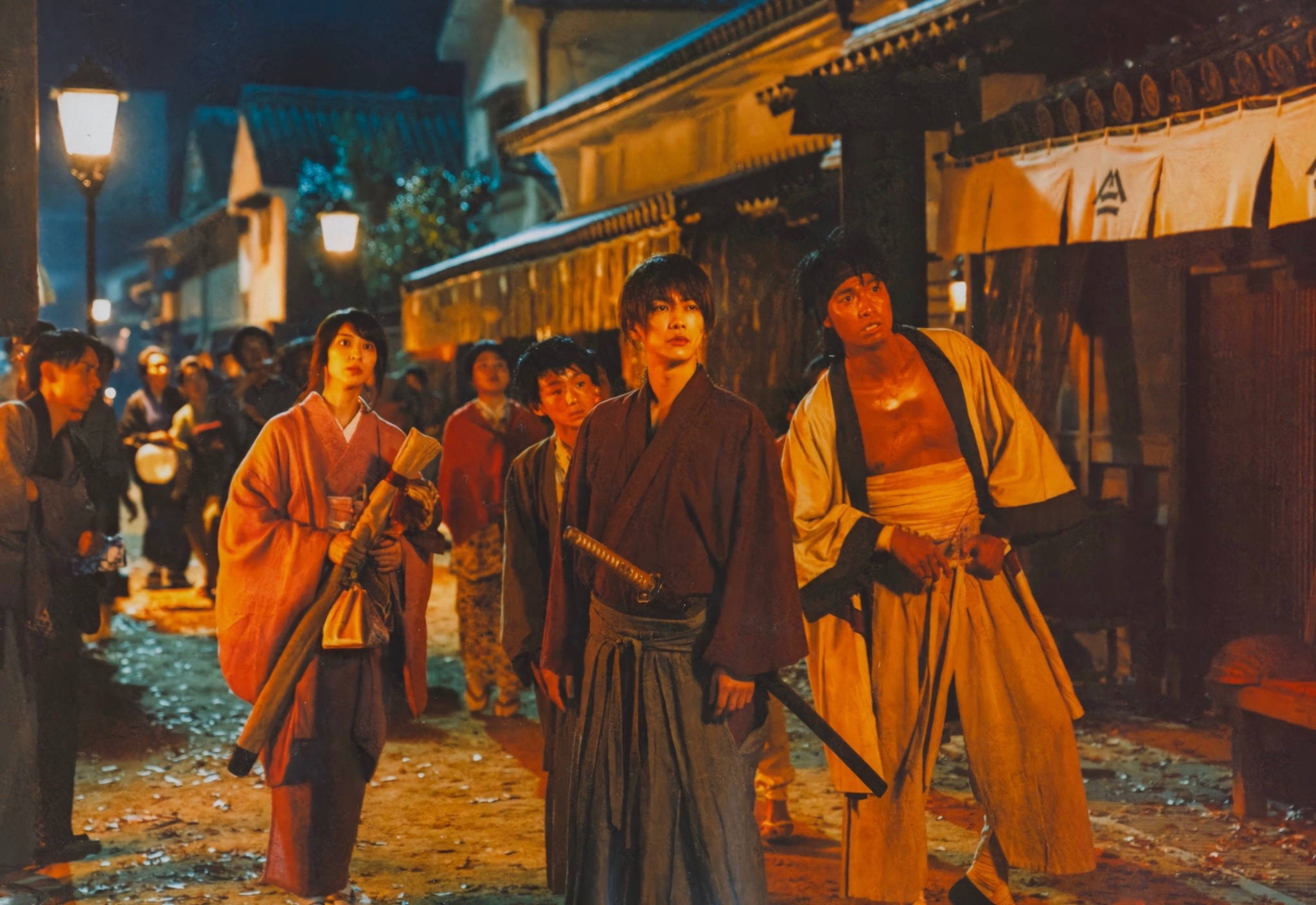 Kenshin 桌布 壁紙 — 一群身穿傳統服飾的武士在夜晚燈籠照亮的日本街道上保持警覺，溫暖的金色燈光投下長長的影子。