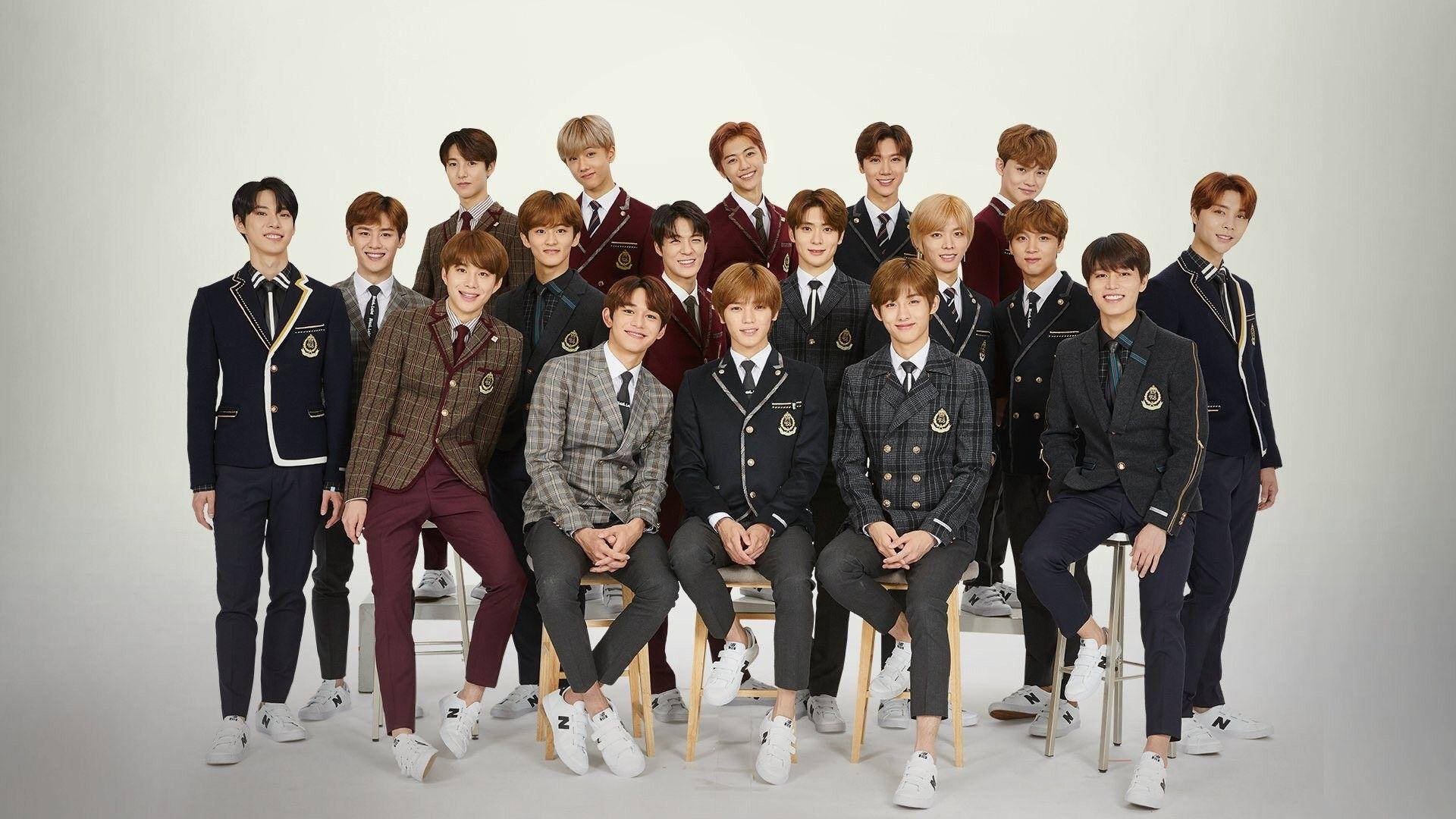 Kpop Aesthetic 桌布 壁紙 — 一群身穿時尚校服的年輕男子在純白背景前自信地擺姿勢拍攝工作室肖像。