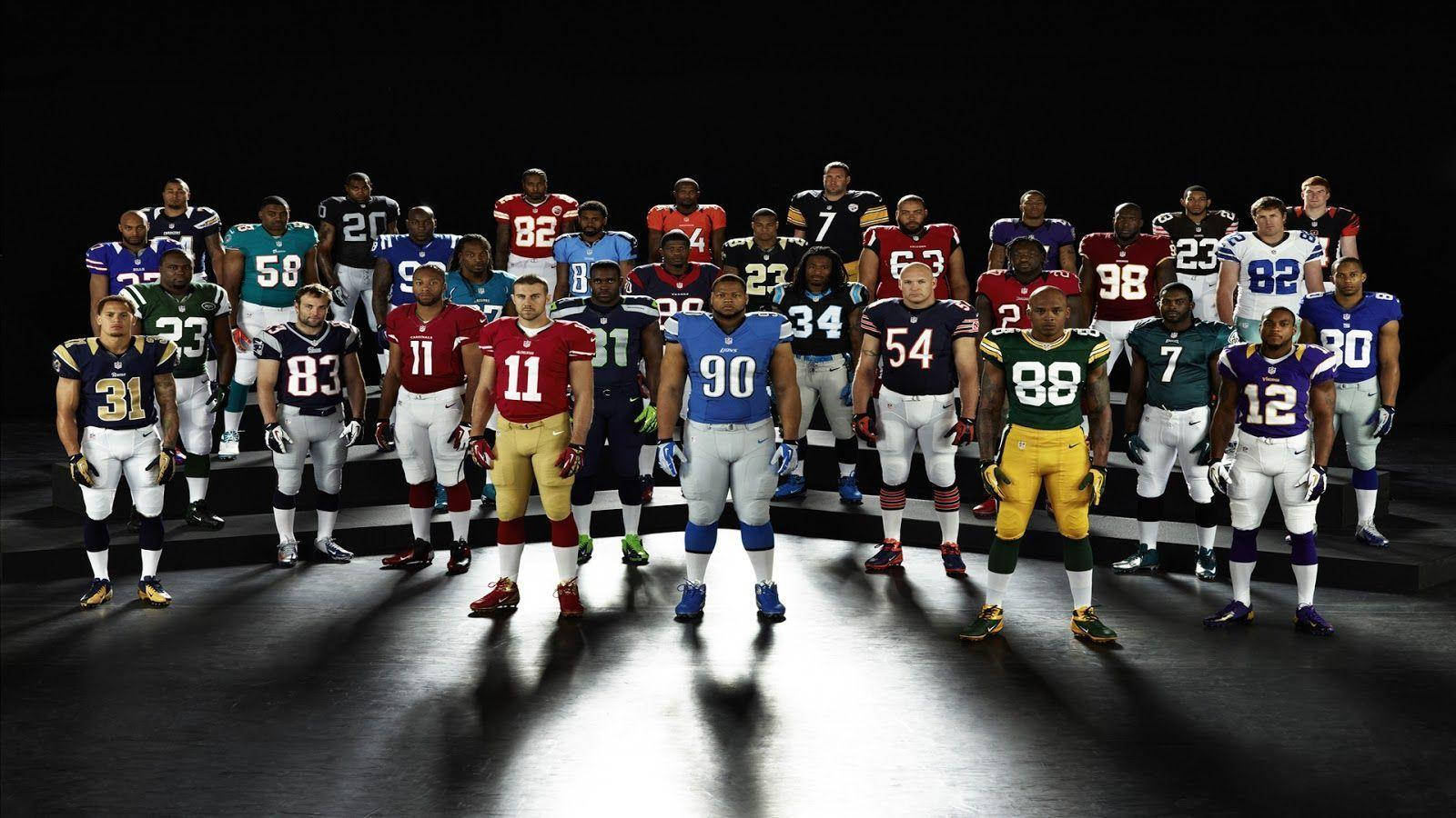 NFL 美式足球 桌布 壁紙 — 一群身穿球隊制服的美式足球NFL球員在黑暗的舞台上，在戲劇性的聚光燈下排成隊形。