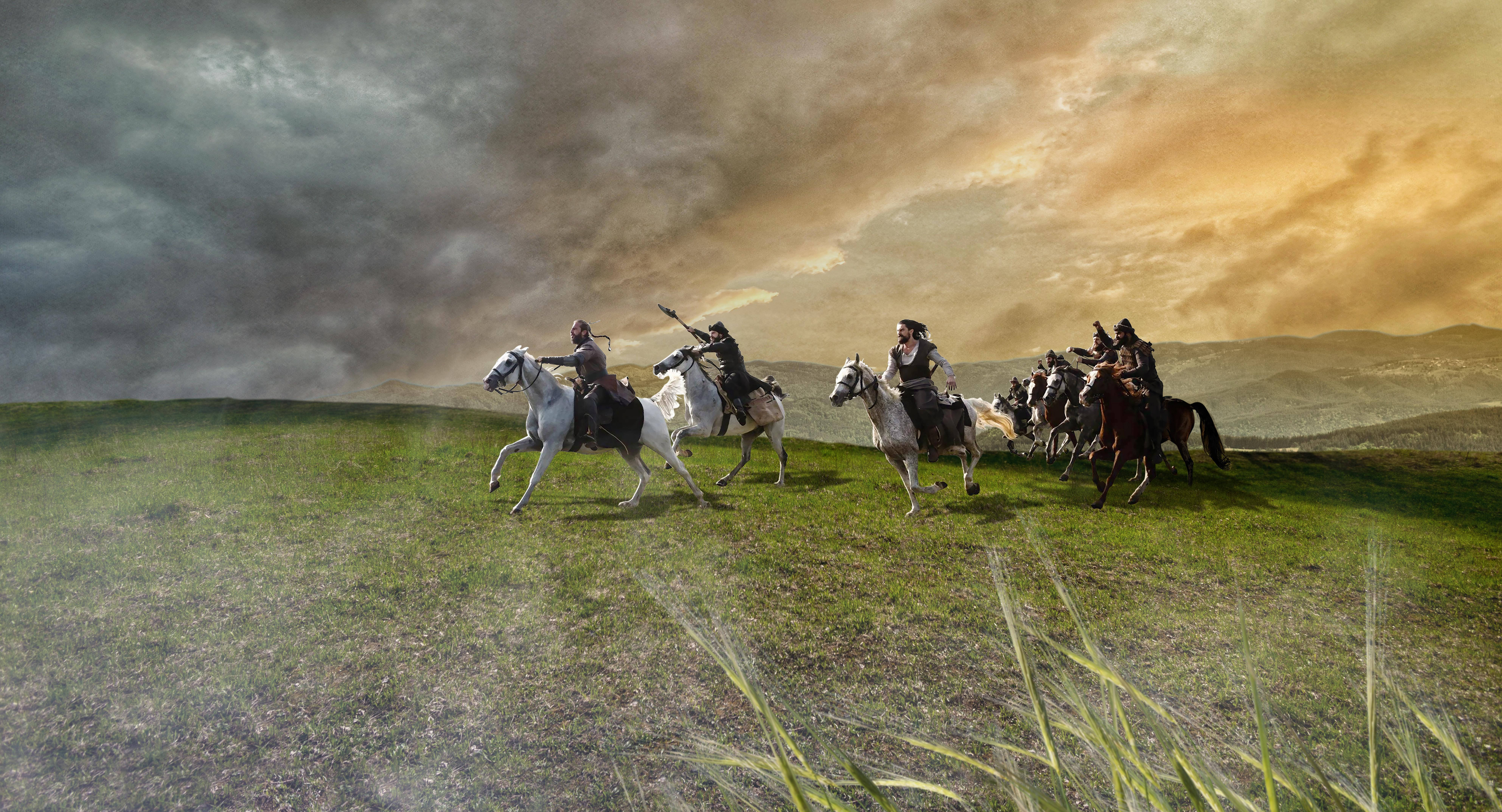 Ertugrul 桌布 壁紙 — 一群身穿盔甲的騎士騎著馬，在戲劇性的暮色天空下奔馳過草地平原。