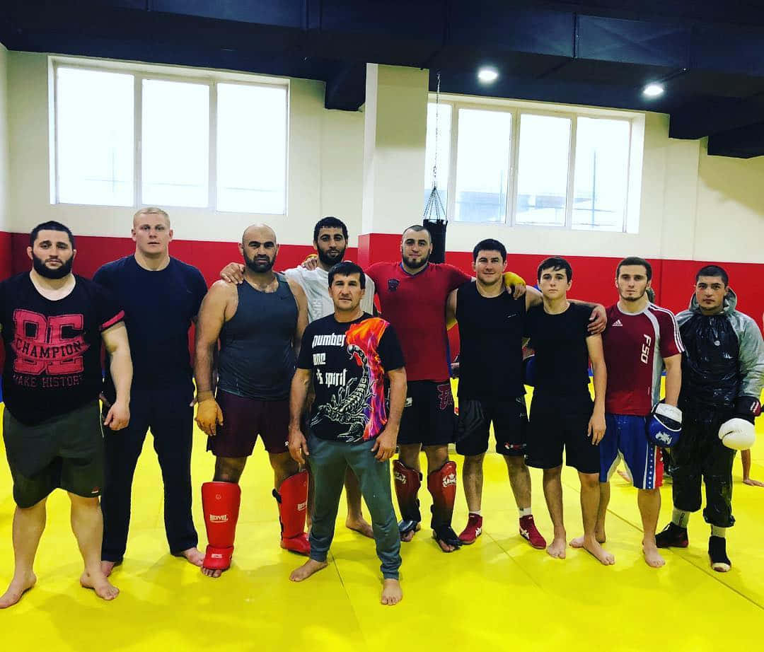 Fitness 桌布 壁紙 — 一群身穿訓練服的男性武術家，在健身房內的亮黃色軟墊上一起擺姿勢。